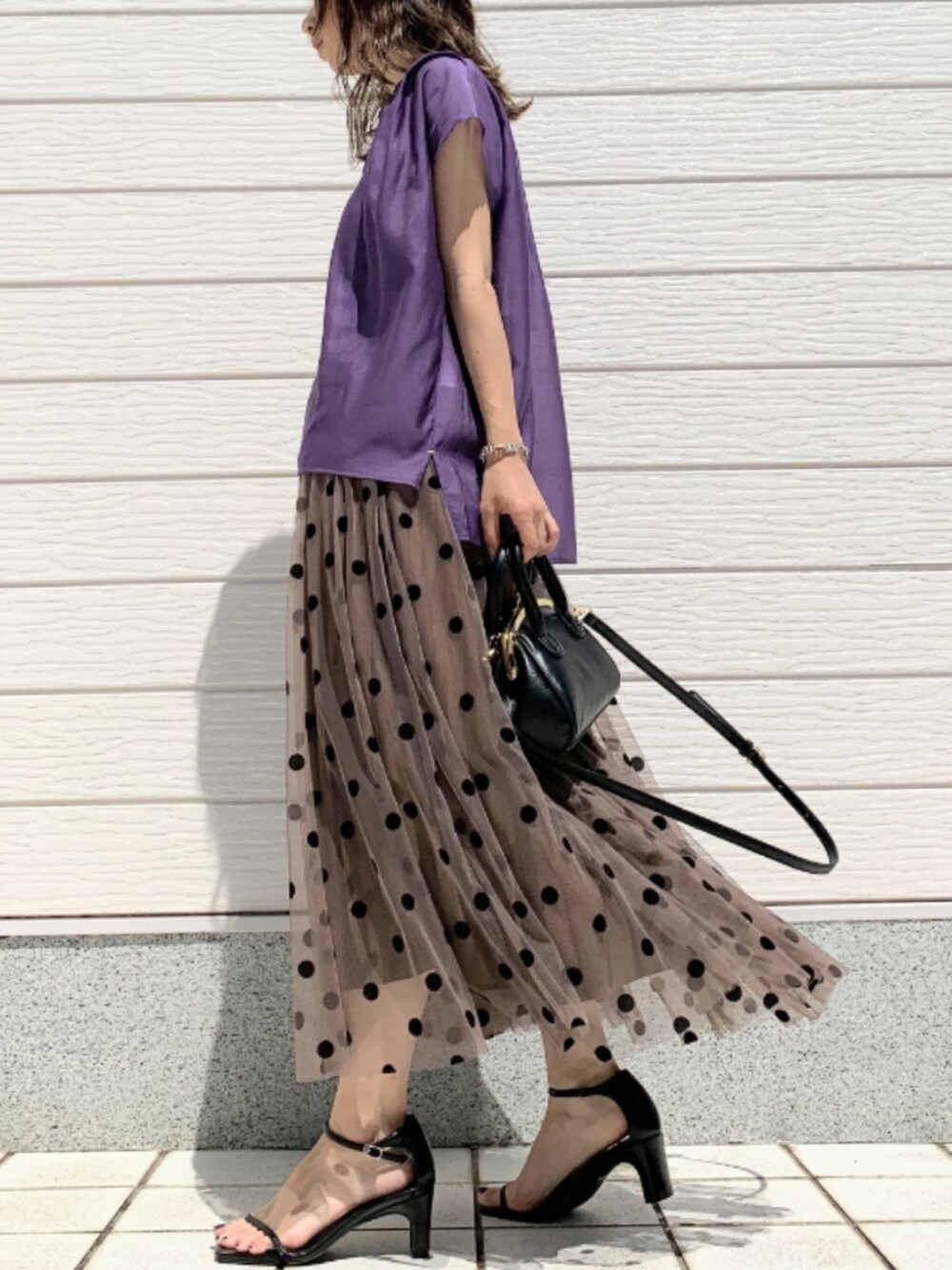 ブラウン系のスカート、ブラック系のショルダーバッグ、パープル系のシャツ/ブラウスを着用したレディースの春コーディネートの2枚目の写真