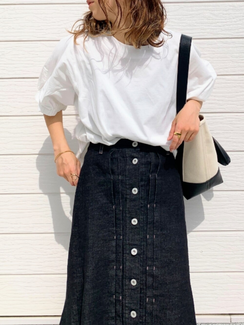 ブラック系のデニムスカート、シルバー系のスニーカー、ホワイト系のTシャツ/カットソーを着用したレディースの春コーディネートの3枚目の写真