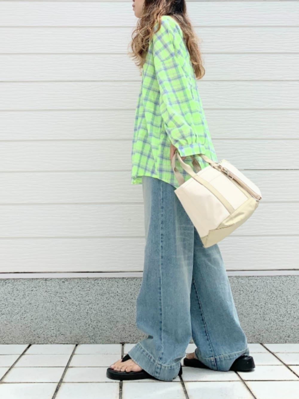 ブルー系のデニムパンツ、ベージュ系のトートバッグ、イエロー系のシャツ/ブラウスを着用したレディースの夏コーディネートの2枚目の写真