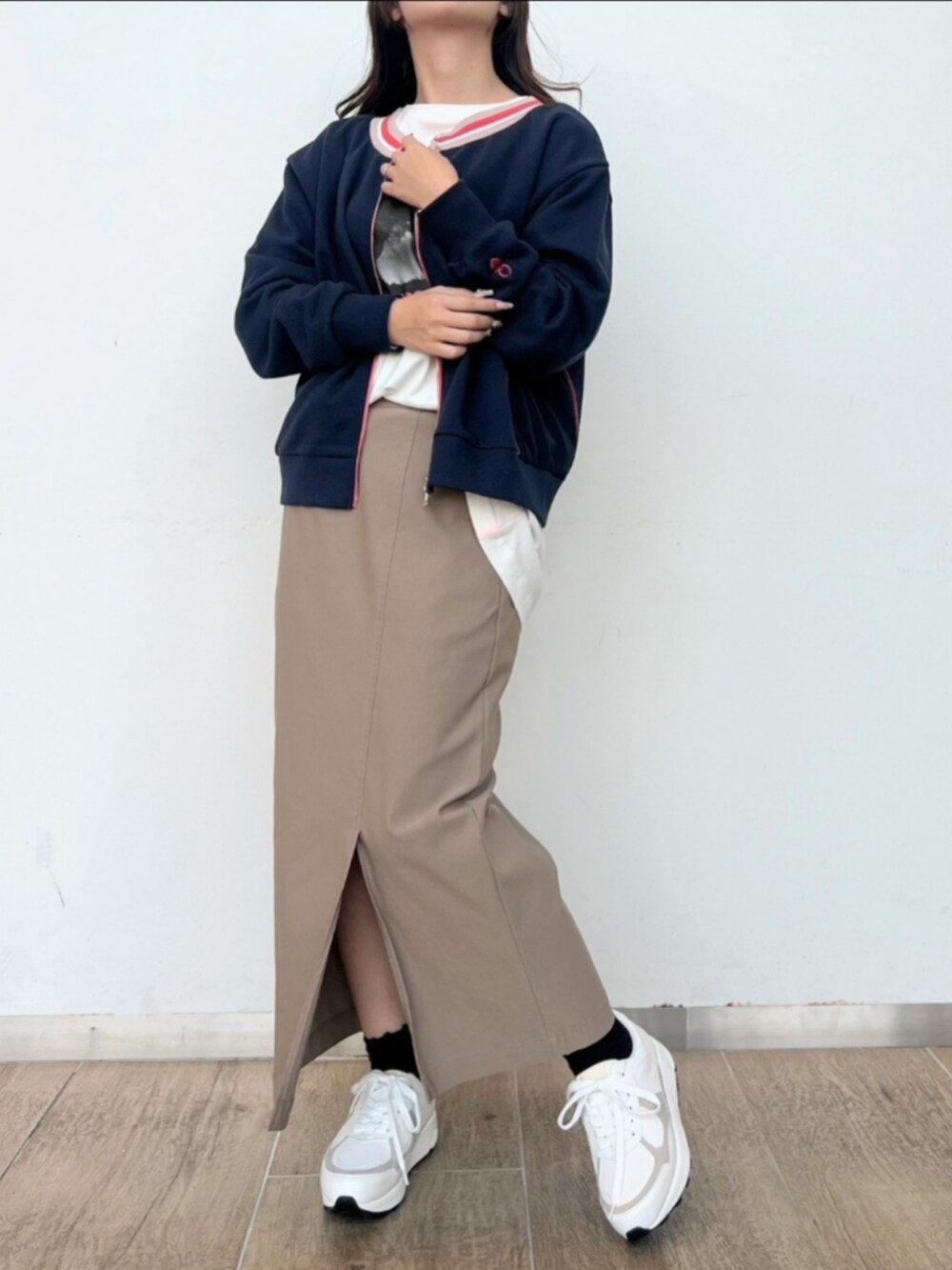 ベージュ系のスカート、ホワイト系のTシャツ/カットソー、ホワイト系のスニーカーを着用したレディースの冬コーディネートの2枚目の写真