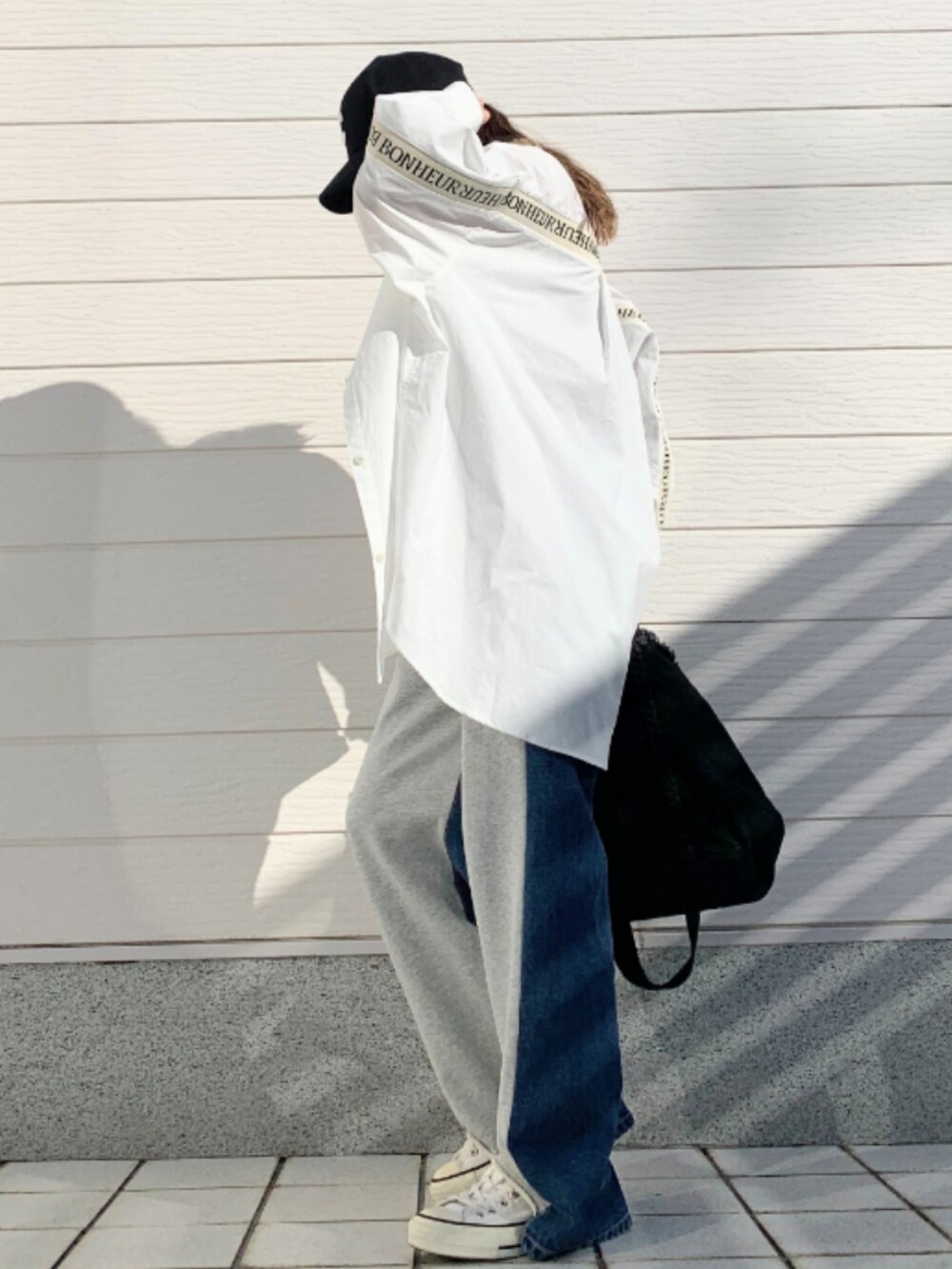 グレー系のデニムパンツ、ブラック系のトートバッグ、ホワイト系のシャツ/ブラウスを着用したレディースの冬コーディネートの2枚目の写真