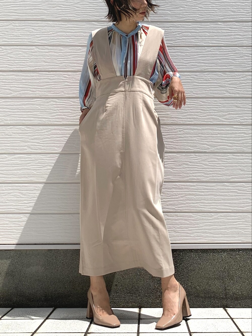 ベージュ系のジャンパースカート、レッド系のシャツ/ブラウスを着用したレディースの夏コーディネートの2枚目の写真