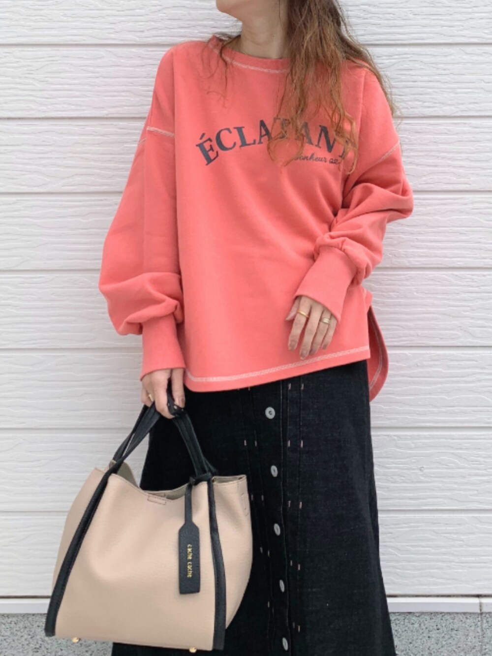 ブラック系のデニムスカート、ホワイト系のスニーカー、ベージュ系のトートバッグを着用したレディースの秋コーディネートの3枚目の写真