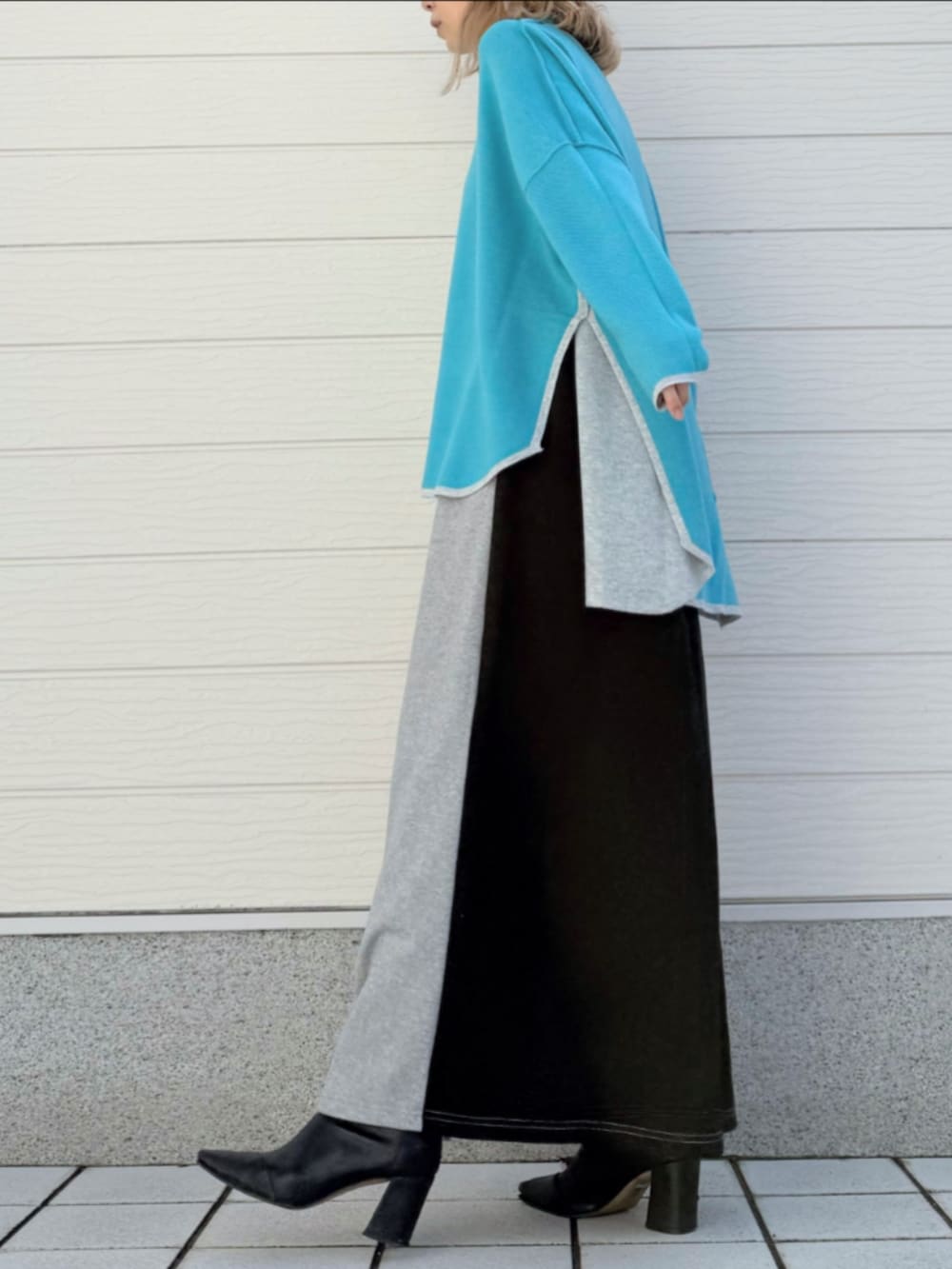 グレー系のニット/セーター、グレー系のスカート、ブラック系のキャップを着用したレディースの秋コーディネートの2枚目の写真