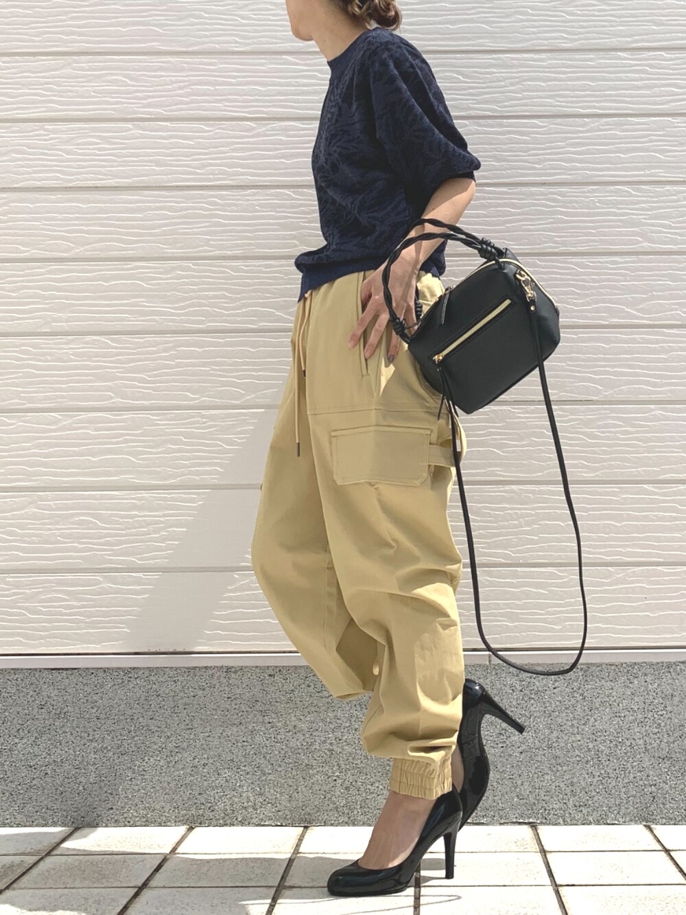 ブラック系のハンドバッグ、ブルー系のニット/セーター、ベージュ系のその他パンツを着用したレディースの春コーディネートの3枚目の写真