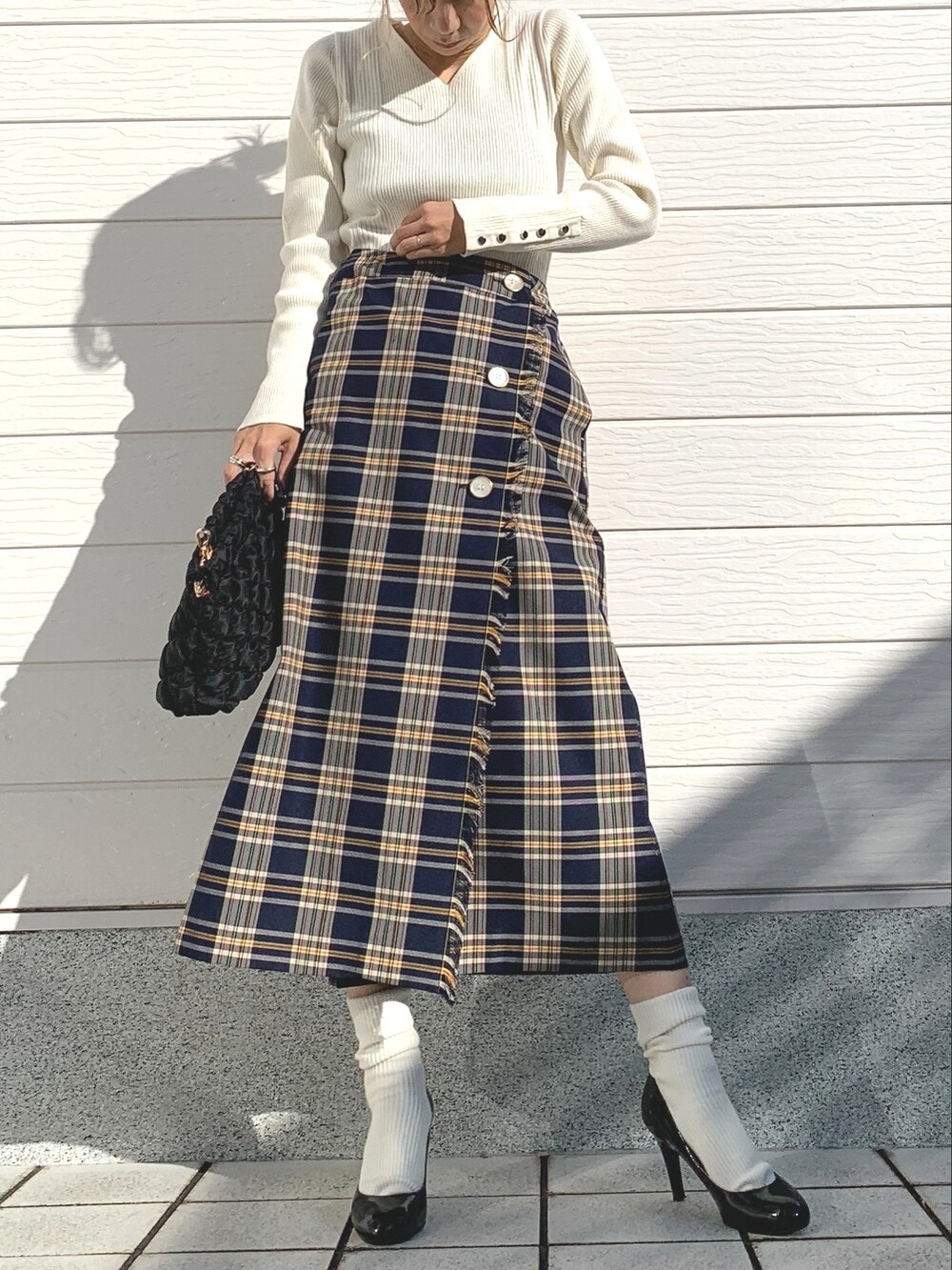ブルー系のスカート、ブラック系のショルダーバッグ、ホワイト系のニット/セーターを着用したレディースの秋コーディネートの2枚目の写真