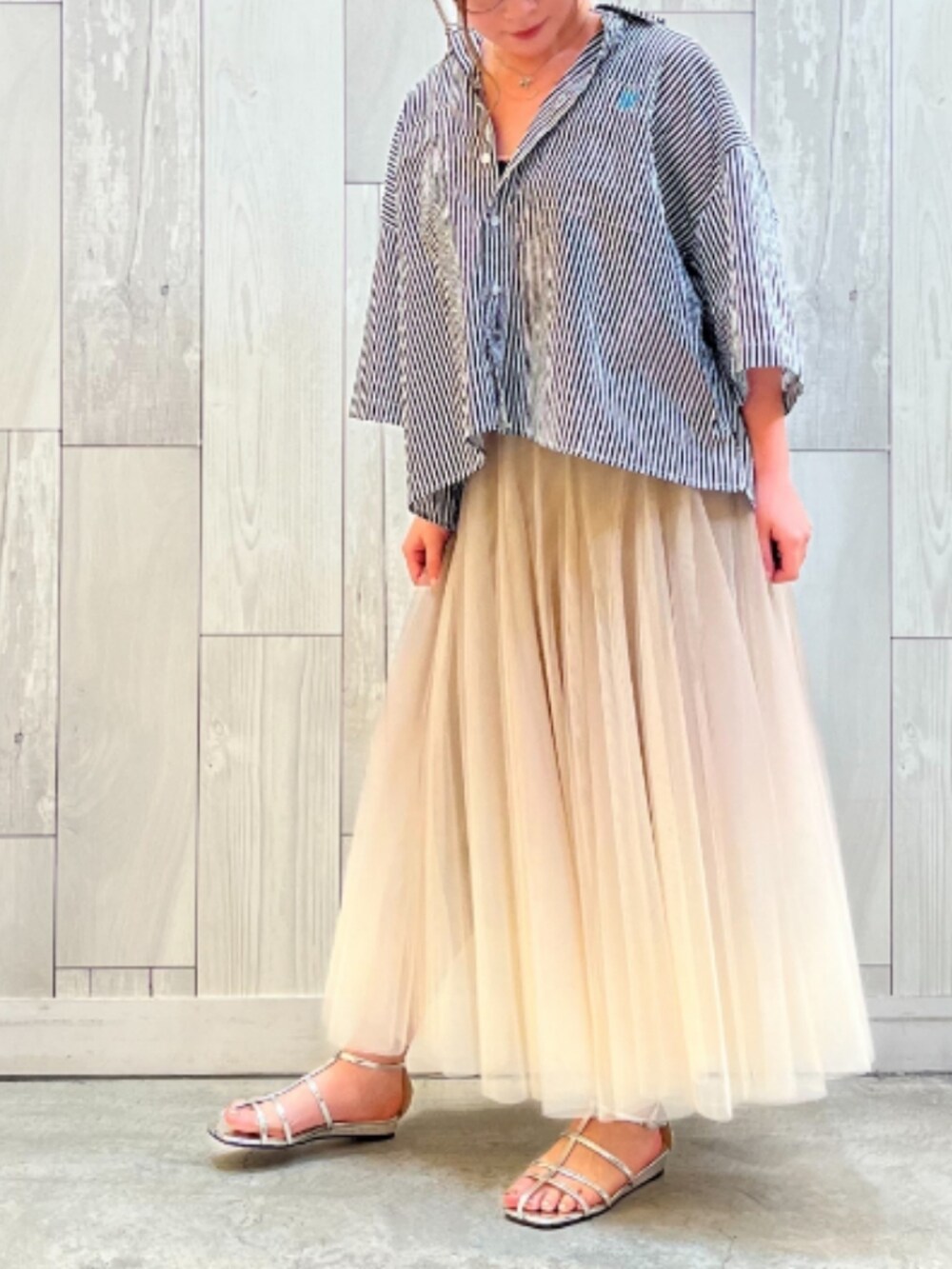 シルバー系のサンダル、ゴールド系のスカート、ブラック系のシャツ/ブラウスを着用したレディースの夏コーディネートの2枚目の写真