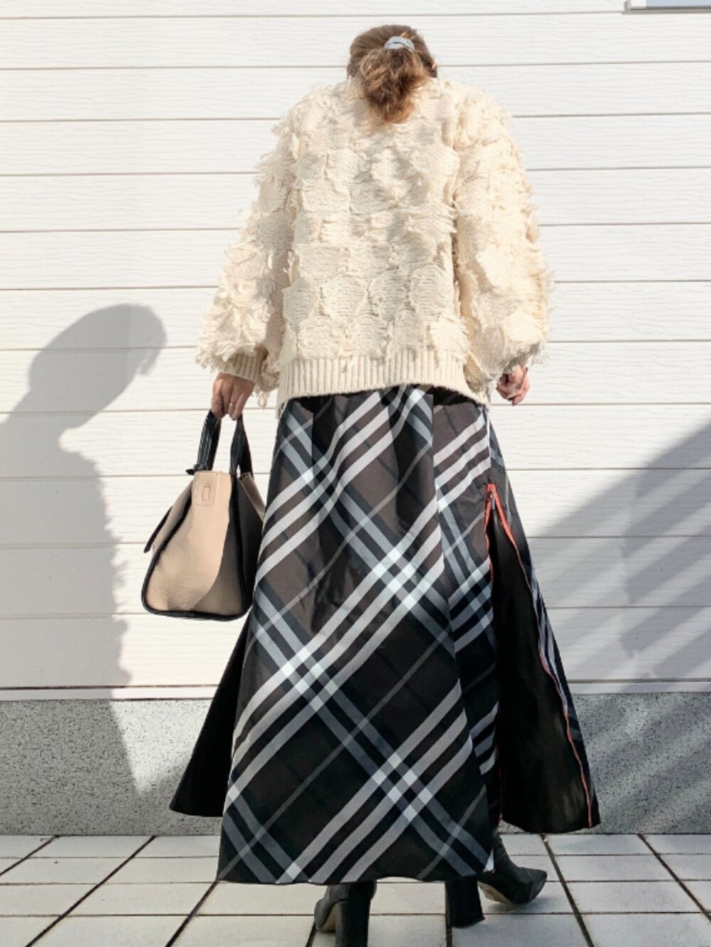 ホワイト系のニット/セーター、ベージュ系のトートバッグ、ブラウン系のスカートを着用したレディースの秋コーディネートの3枚目の写真