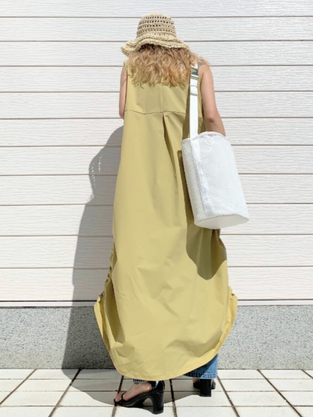 ブルー系のデニムパンツ、イエロー系のワンピース、ホワイト系のショルダーバッグを着用したレディースの春コーディネートの3枚目の写真