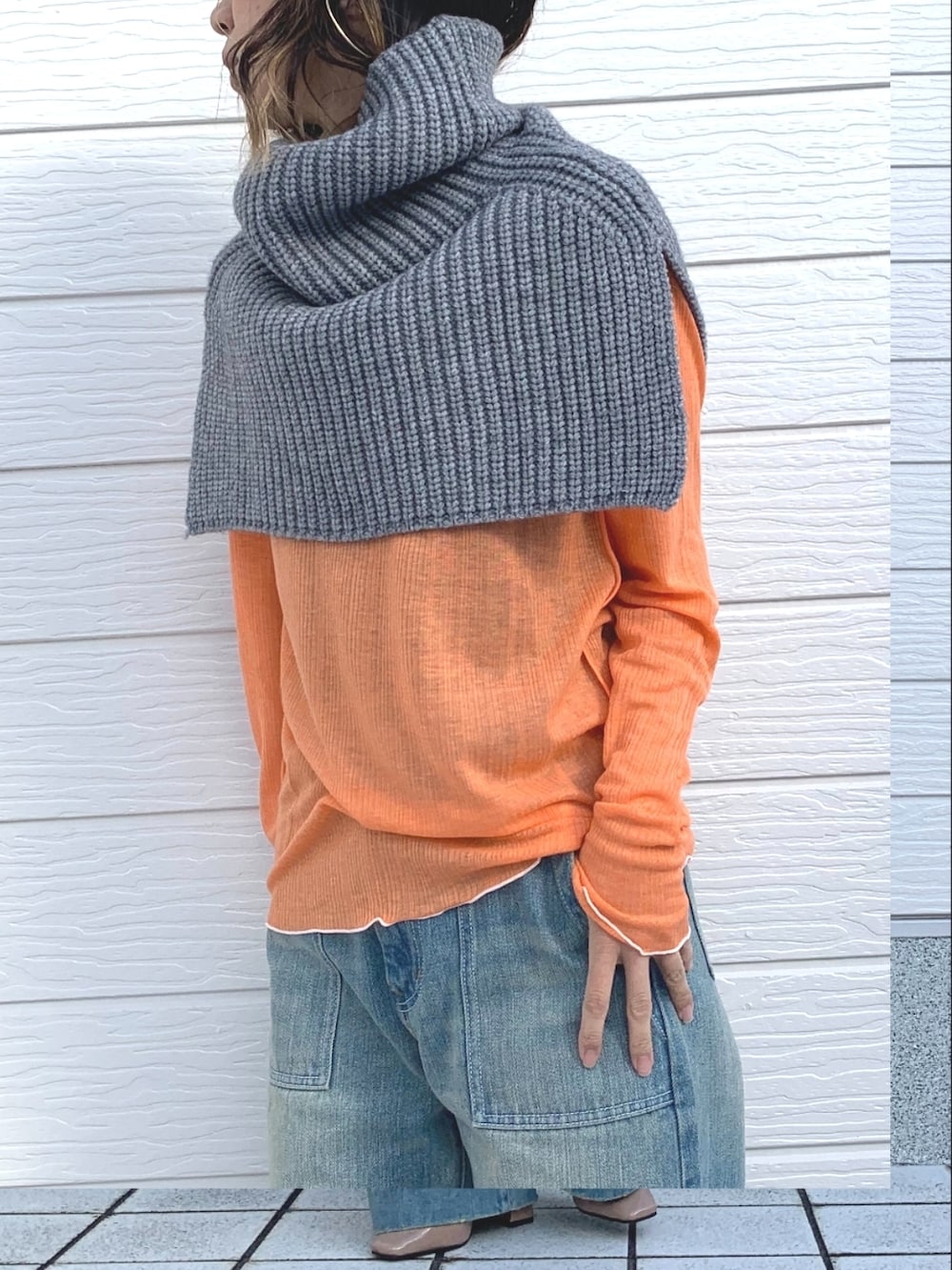 オレンジ系のTシャツ/カットソー、ブルー系のデニムパンツ、グレー系のネックウォーマー/スヌードを着用したレディースの冬コーディネートの4枚目の写真