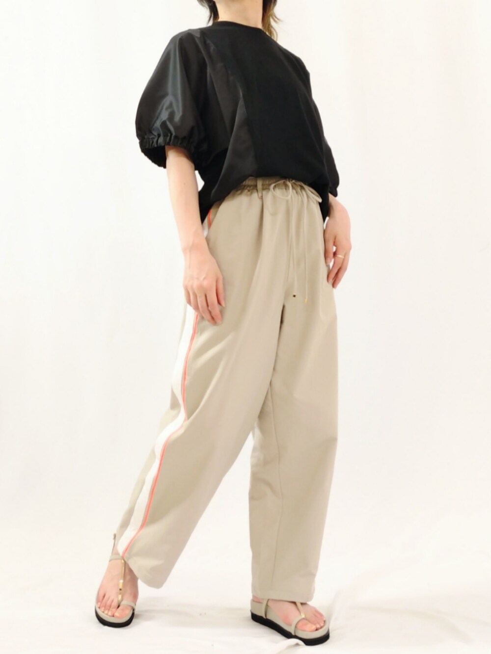 ベージュ系のその他パンツ、ブラック系のTシャツ/カットソー、グレー系のサンダルを着用したレディースの春コーディネートの2枚目の写真