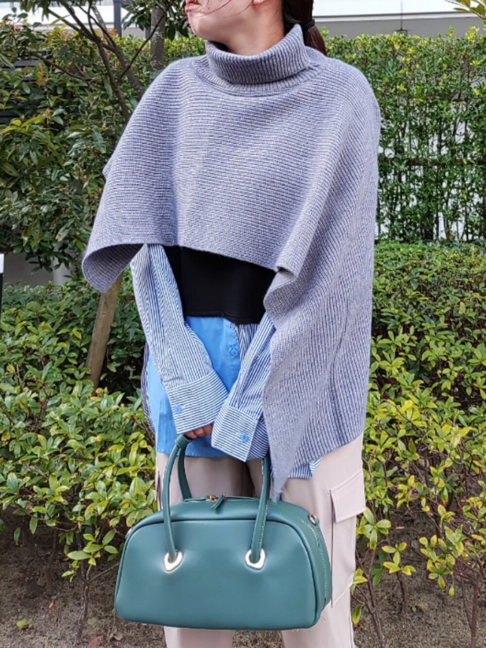 ベージュ系のカーゴパンツ、ブラック系のスニーカー、グリーン系のボストンバッグを着用したレディースの秋コーディネートの3枚目の写真