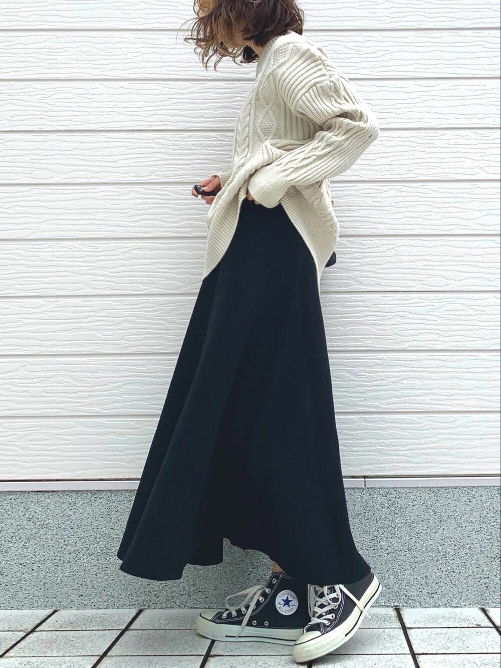 ブラック系のショルダーバッグ、ブラック系のスニーカー、ホワイト系のニット/セーターを着用したレディースの冬コーディネートの3枚目の写真