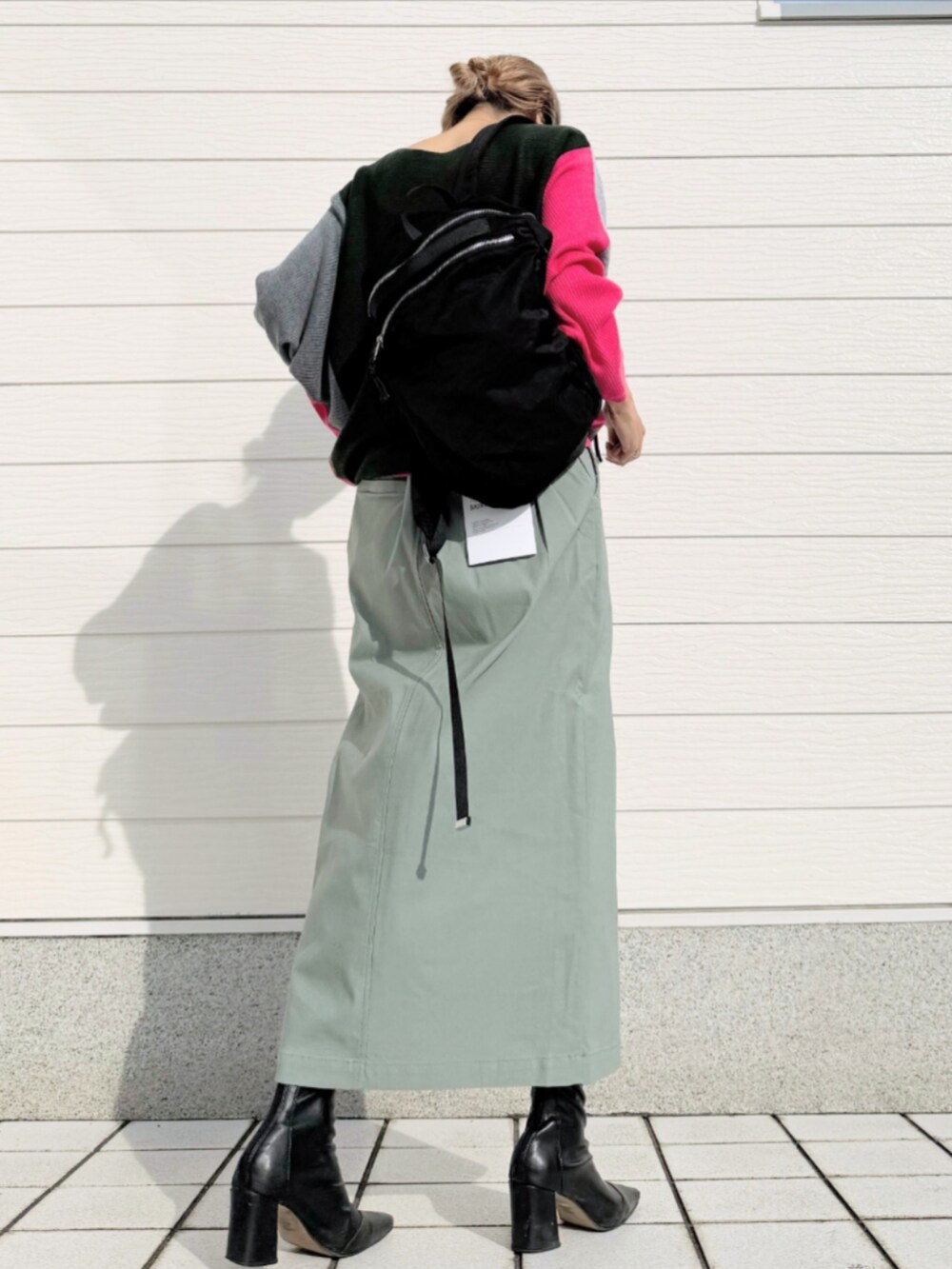 グリーン系のスカート、ブラック系のバックパック/リュック、グレー系のニット/セーターを着用したレディースの秋コーディネートの2枚目の写真