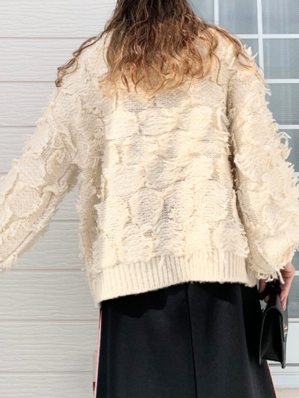 ブラック系のスカート、ホワイト系のニット/セーターを着用したレディースの秋コーディネートの5枚目の写真