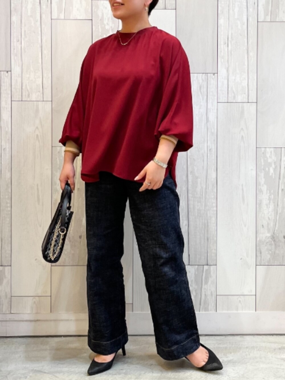 ブルー系のデニムパンツ、レッド系のシャツ/ブラウス、ブラック系のショルダーバッグを着用したレディースの秋コーディネートの2枚目の写真