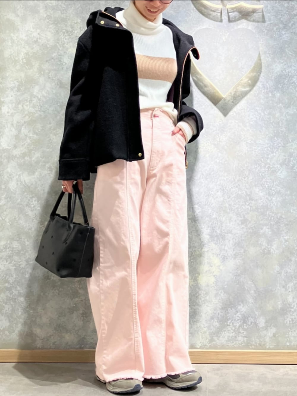 ブラック系のトートバッグ、ピンク系のデニムパンツ、ホワイト系のニット/セーターを着用したレディースの冬コーディネートの2枚目の写真