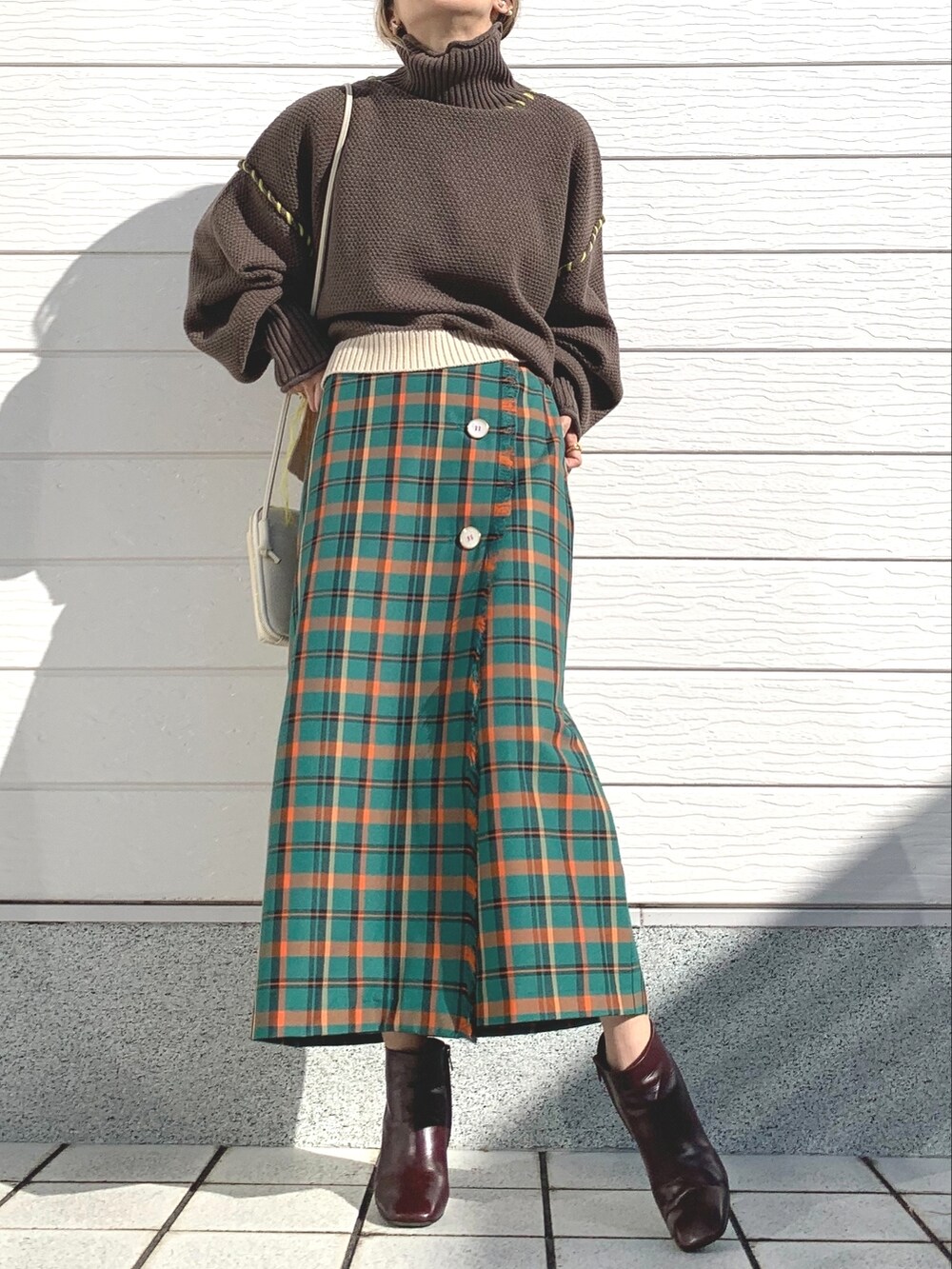 ブラウン系のニット/セーター、グリーン系のスカート、ブラウン系のブーツを着用したレディースの秋コーディネートの2枚目の写真