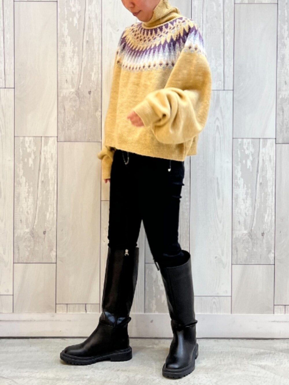 ブラック系のブーツ、ブラック系のデニムパンツ、イエロー系のニット/セーターを着用したレディースの秋コーディネートの2枚目の写真