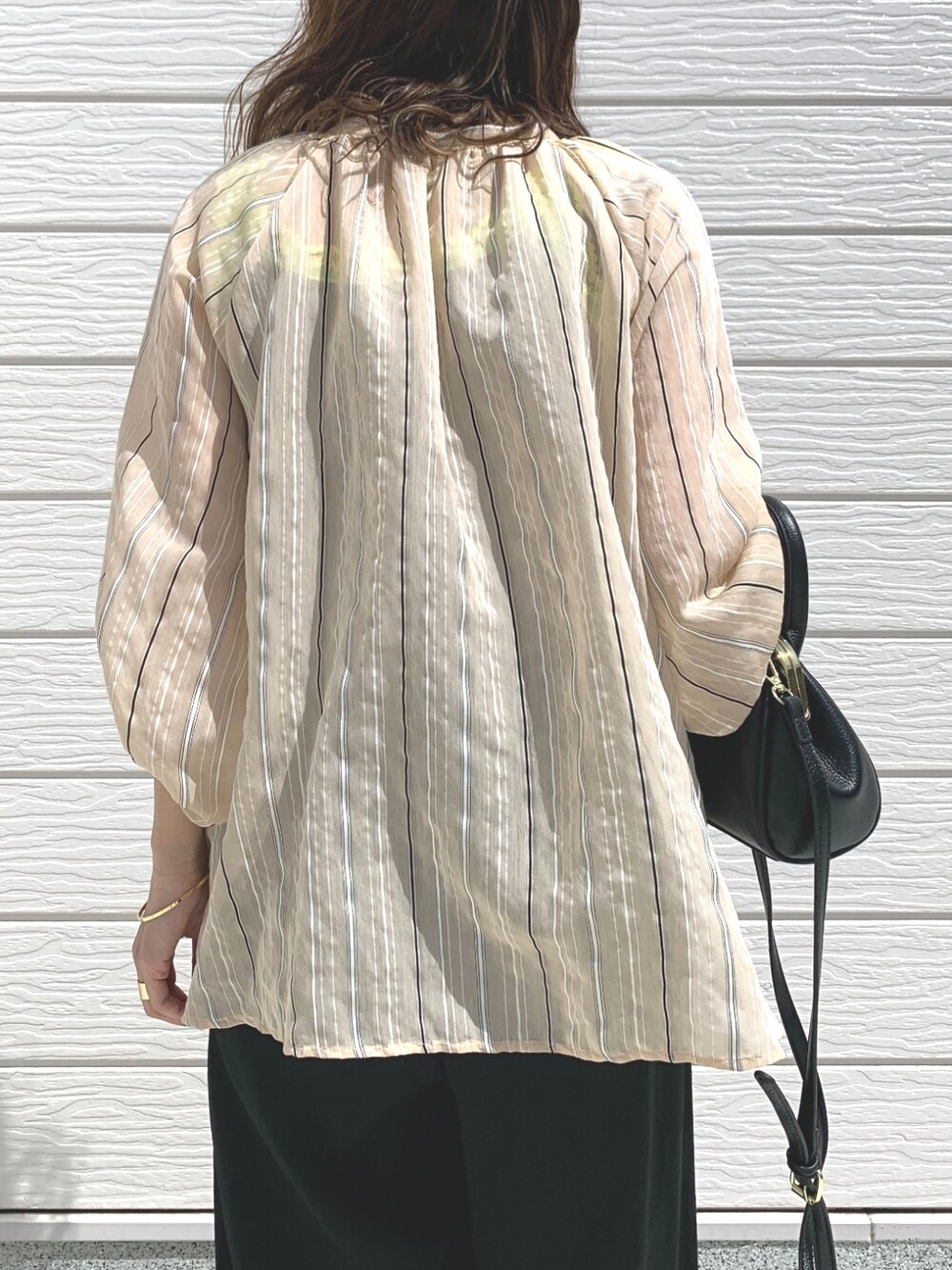 ブラック系のその他パンツ、ブラック系のショルダーバッグ、ベージュ系のシャツ/ブラウスを着用したレディースの春コーディネートの5枚目の写真