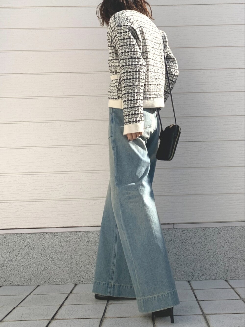 ブルー系のデニムパンツ、ホワイト系のカーディガン/ボレロ、ブラック系のショルダーバッグを着用したレディースの冬コーディネートの2枚目の写真