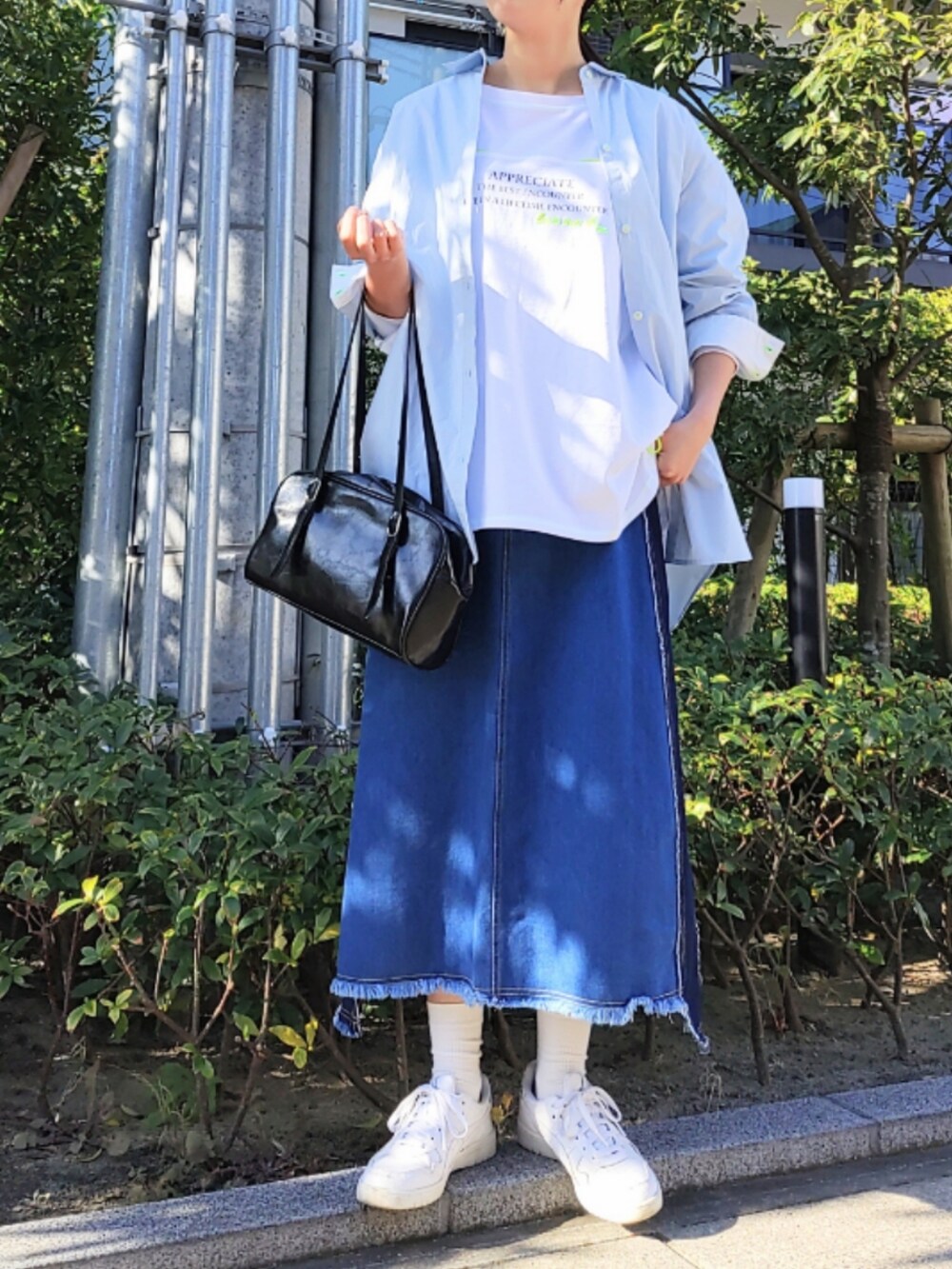 ブルー系のデニムスカート、ホワイト系のスニーカー、ホワイト系のTシャツ/カットソーを着用したレディースの冬コーディネートの2枚目の写真