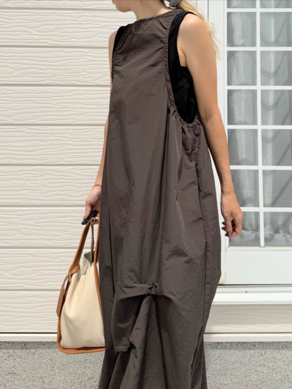 ブラック系のサンダル、ホワイト系のハンドバッグ、グレー系のワンピースを着用したレディースの夏コーディネートの4枚目の写真