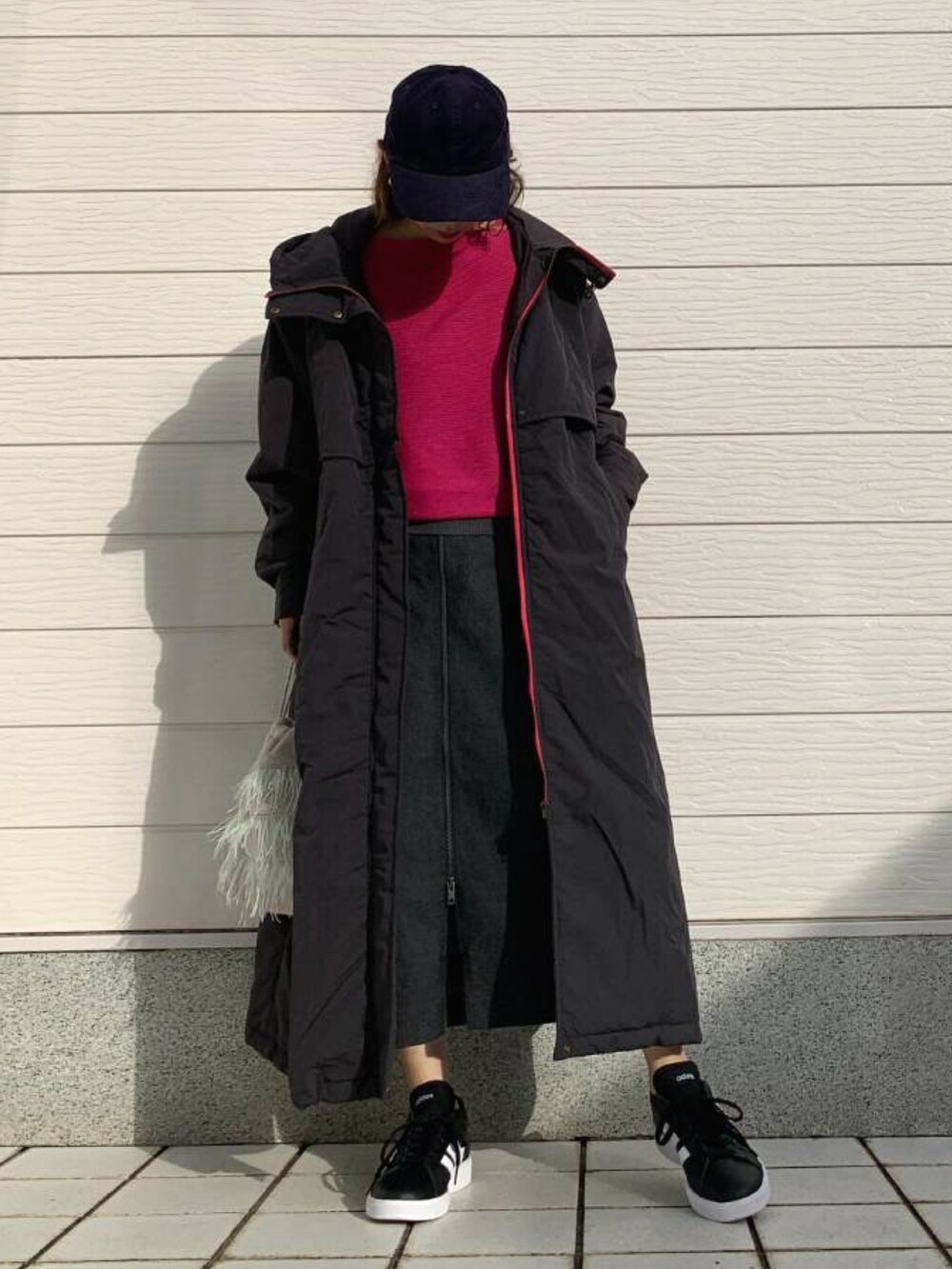 グレー系のクラッチバッグ、ブラック系のスニーカー、ブルー系のスカートを着用したレディースの秋コーディネートの2枚目の写真