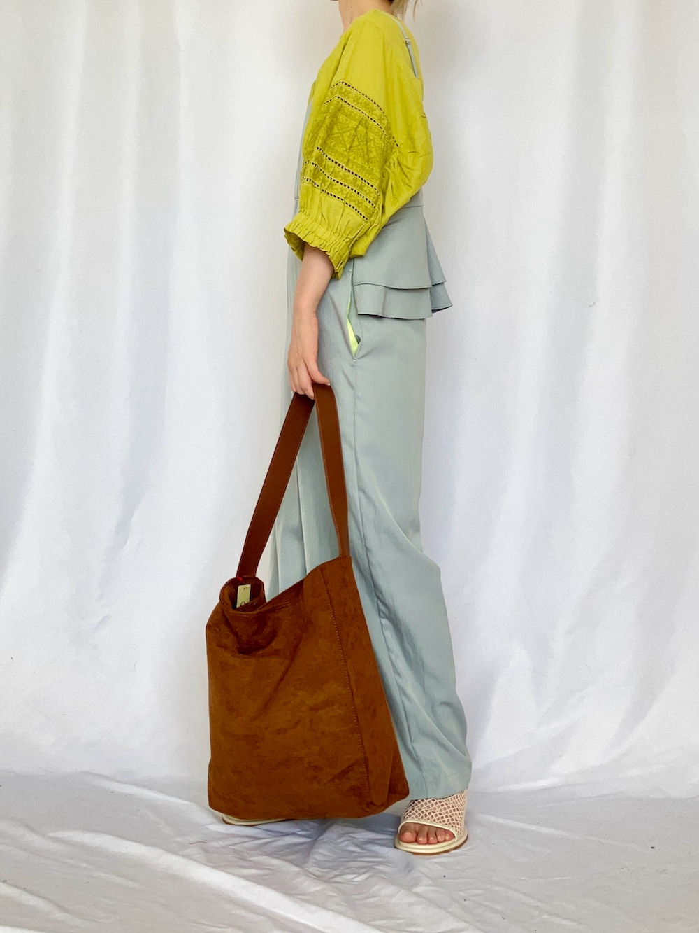 イエロー系のトートバッグ、ブルー系のサロペット/オーバーオール、グレー系のサンダルを着用したレディースの夏コーディネートの3枚目の写真