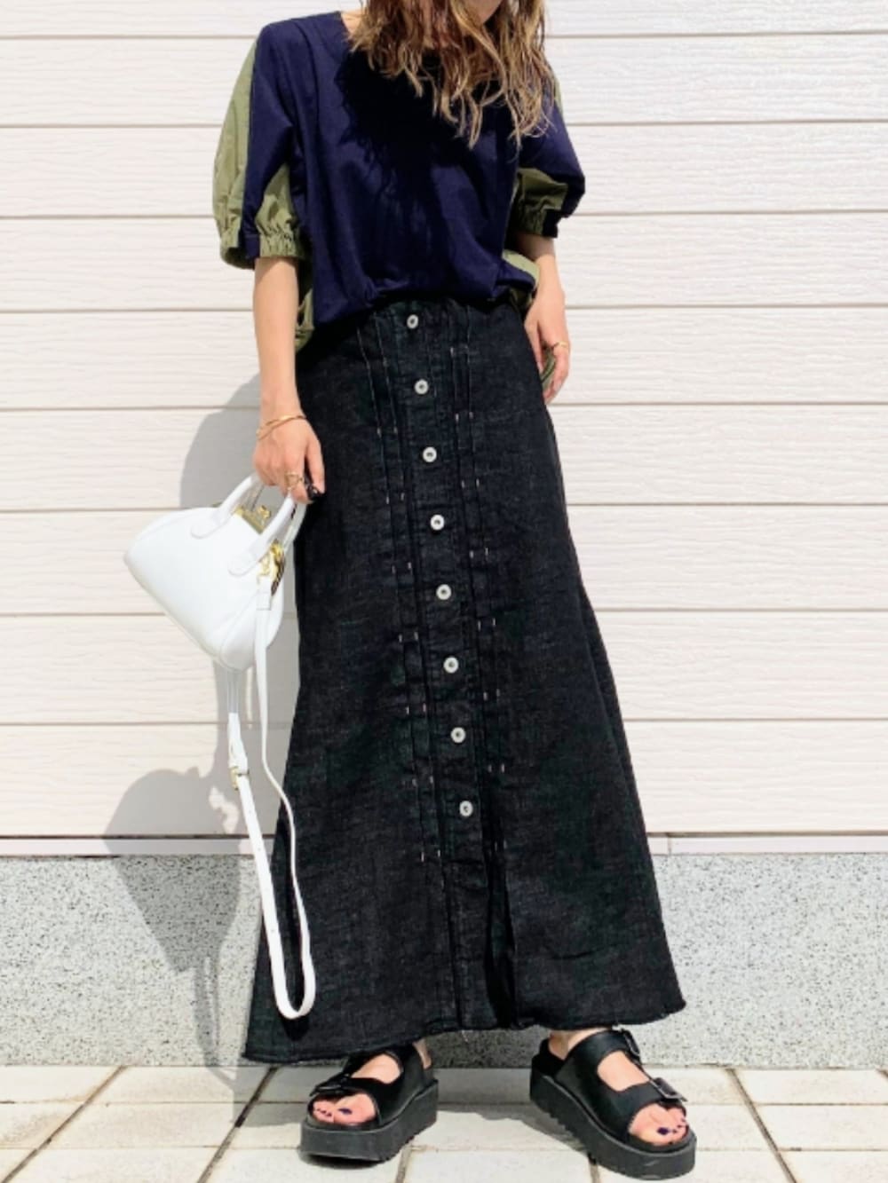 ブラック系のデニムスカート、ブラック系のサンダル、ホワイト系のショルダーバッグを着用したレディースの春コーディネートの2枚目の写真