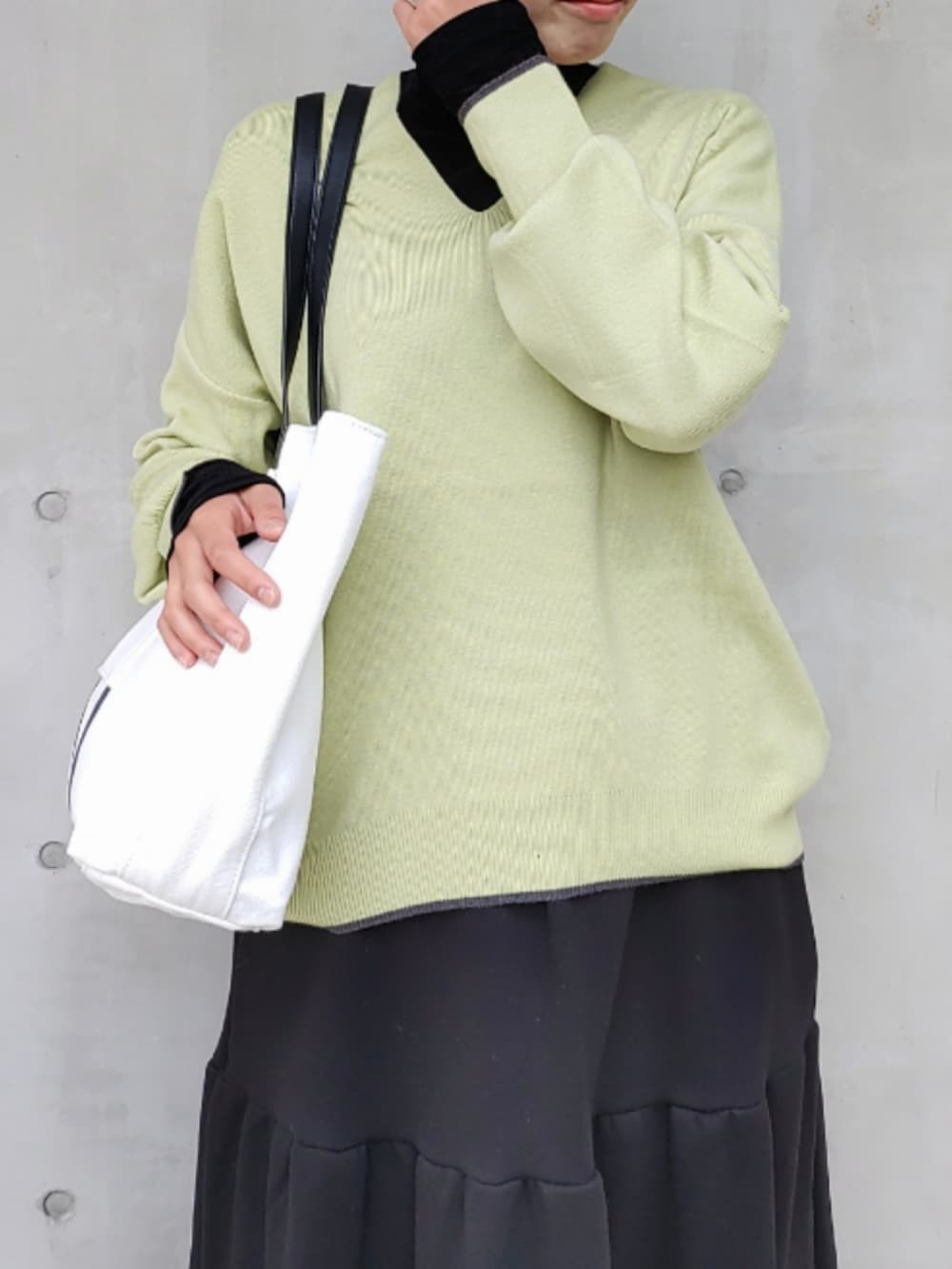 ブラック系のスカート、ブラック系のスニーカー、グリーン系のニット/セーターを着用したレディースの秋コーディネートの4枚目の写真