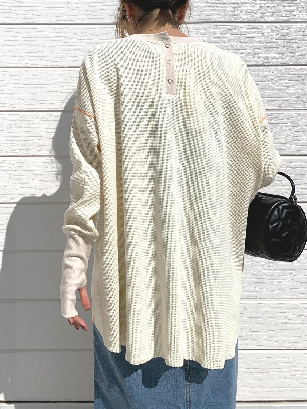 ブラック系のドラムバッグ、ブルー系のデニムスカート、ホワイト系のTシャツ/カットソーを着用したレディースの秋コーディネートの4枚目の写真