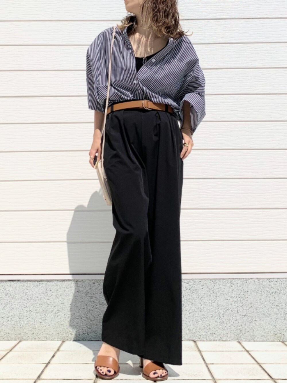ブラック系のその他パンツ、ブラック系のシャツ/ブラウス、ブラウン系のサンダルを着用したレディースの春コーディネートの2枚目の写真