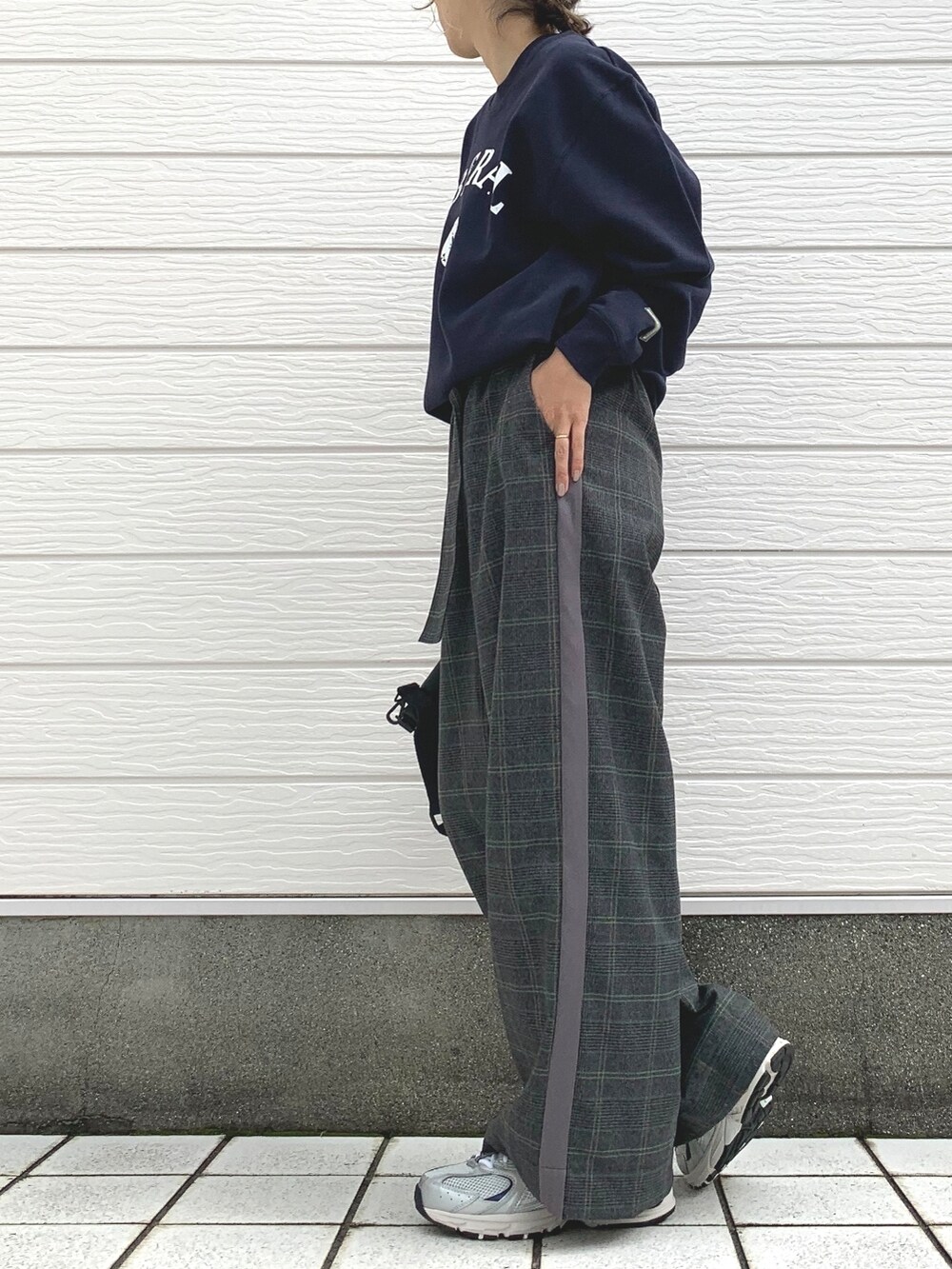 ブラック系のクラッチバッグ、シルバー系のスニーカー、ブルー系のスウェットを着用したレディースの秋コーディネートの2枚目の写真