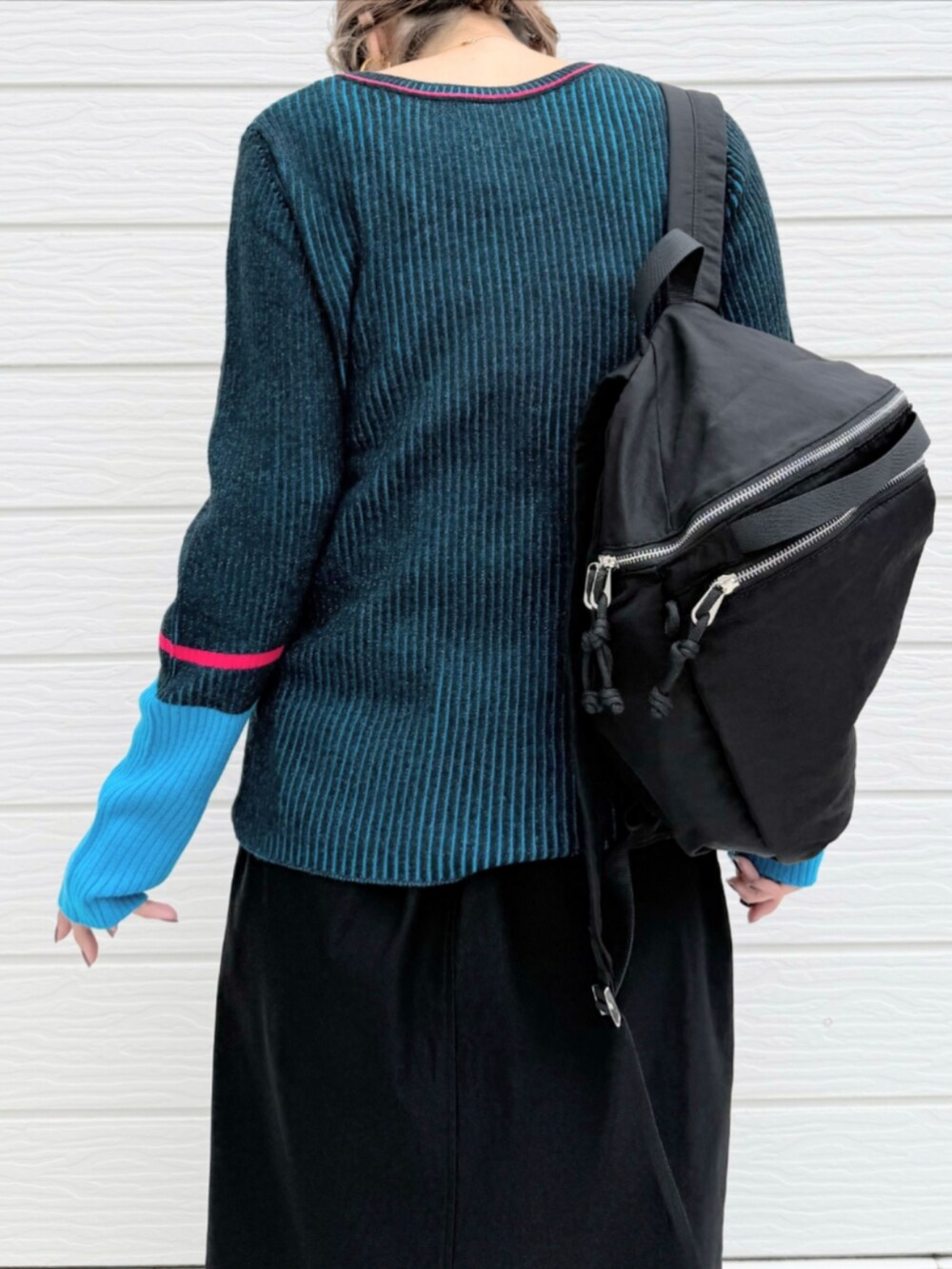 ブラック系のスカート、ブラック系のバックパック/リュック、ブラック系のニット/セーターを着用したレディースの秋コーディネートの5枚目の写真