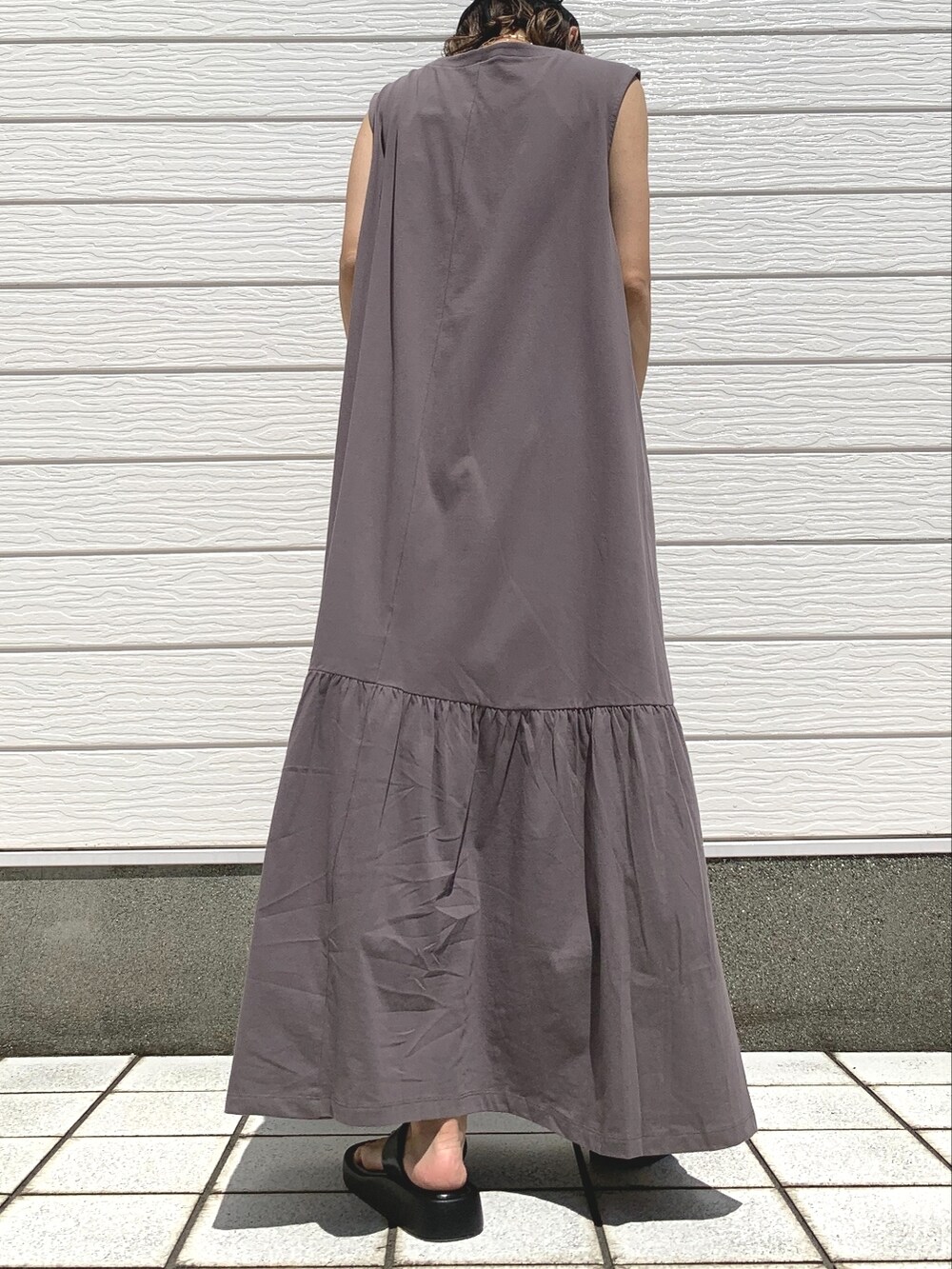 グレー系のワンピース、ブラック系のキャップ、ゴールド系のネックレスを着用したレディースの夏コーディネートの2枚目の写真