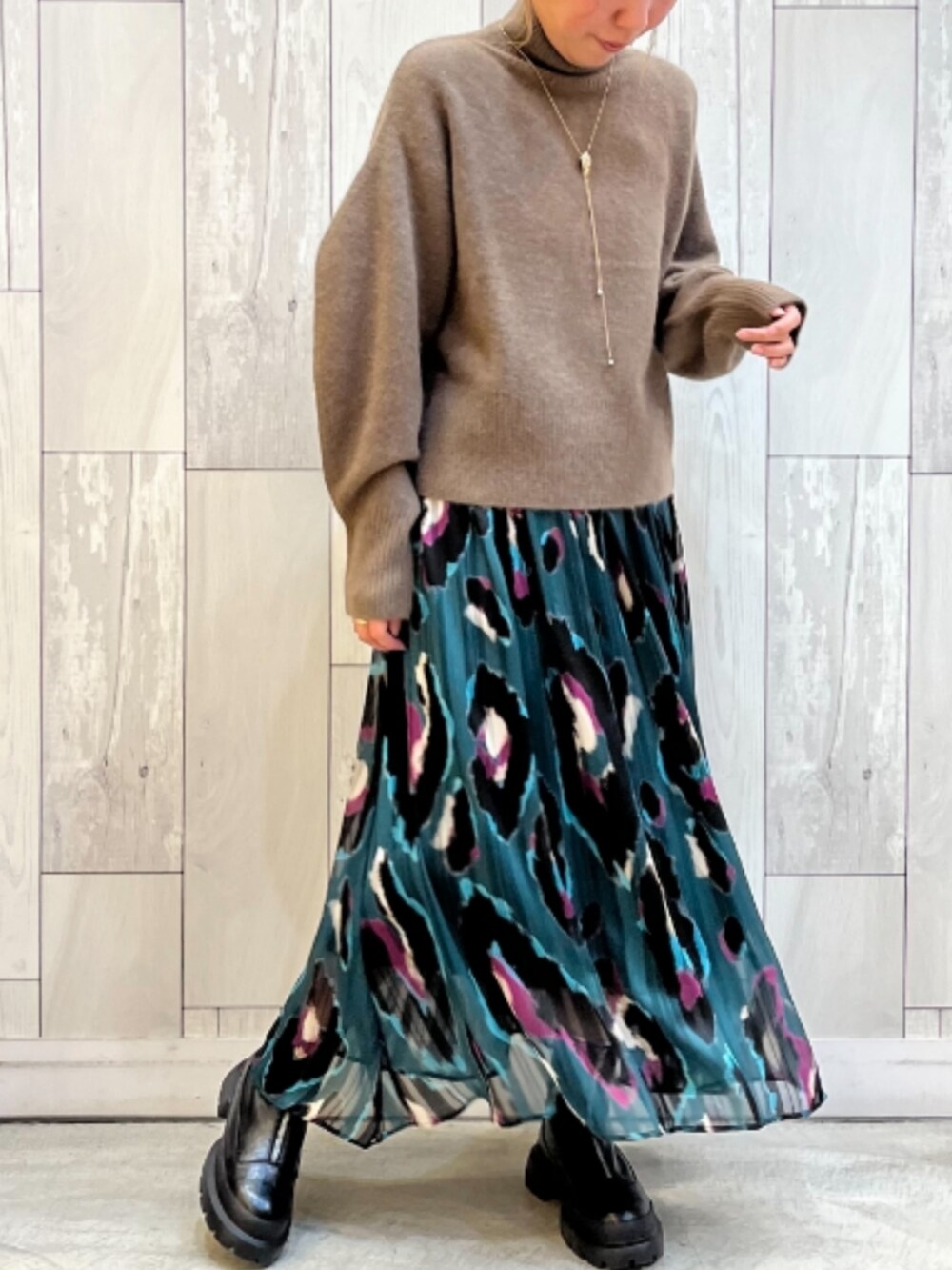 ブラック系のブーツ、グリーン系のスカート、ブラウン系のニット/セーターを着用したレディースの冬コーディネートの2枚目の写真