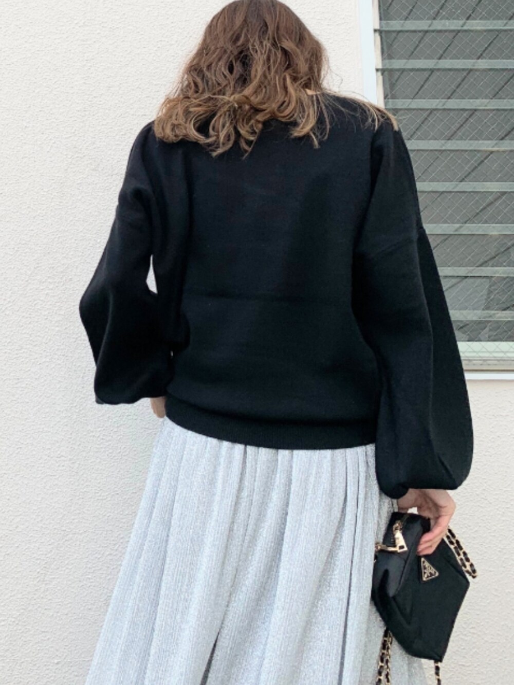 シルバー系のスカート、シルバー系のスニーカー、ブラック系のニット/セーターを着用したレディースの冬コーディネートの4枚目の写真