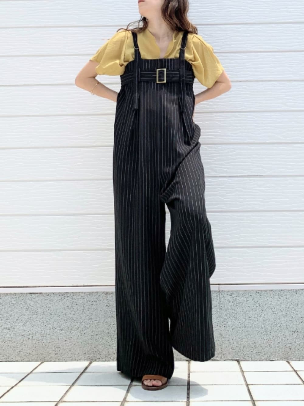 ブラウン系のサンダル、イエロー系のシャツ/ブラウス、ブラック系のサロペット/オーバーオールを着用したレディースの夏コーディネートの2枚目の写真