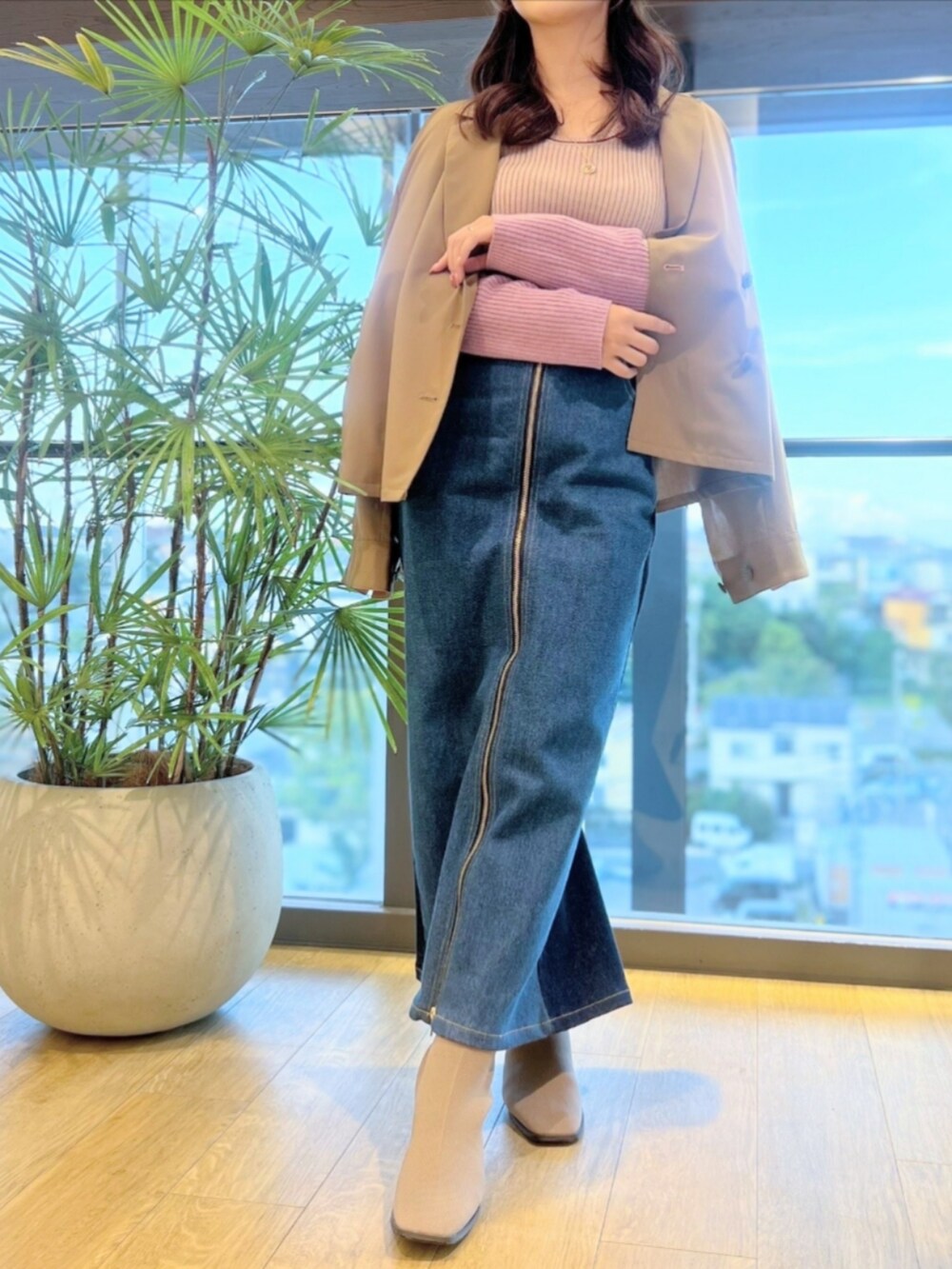 ブルー系のデニムパンツ、ベージュ系のブーツ、ピンク系のニット/セーターを着用したレディースの秋コーディネートの2枚目の写真