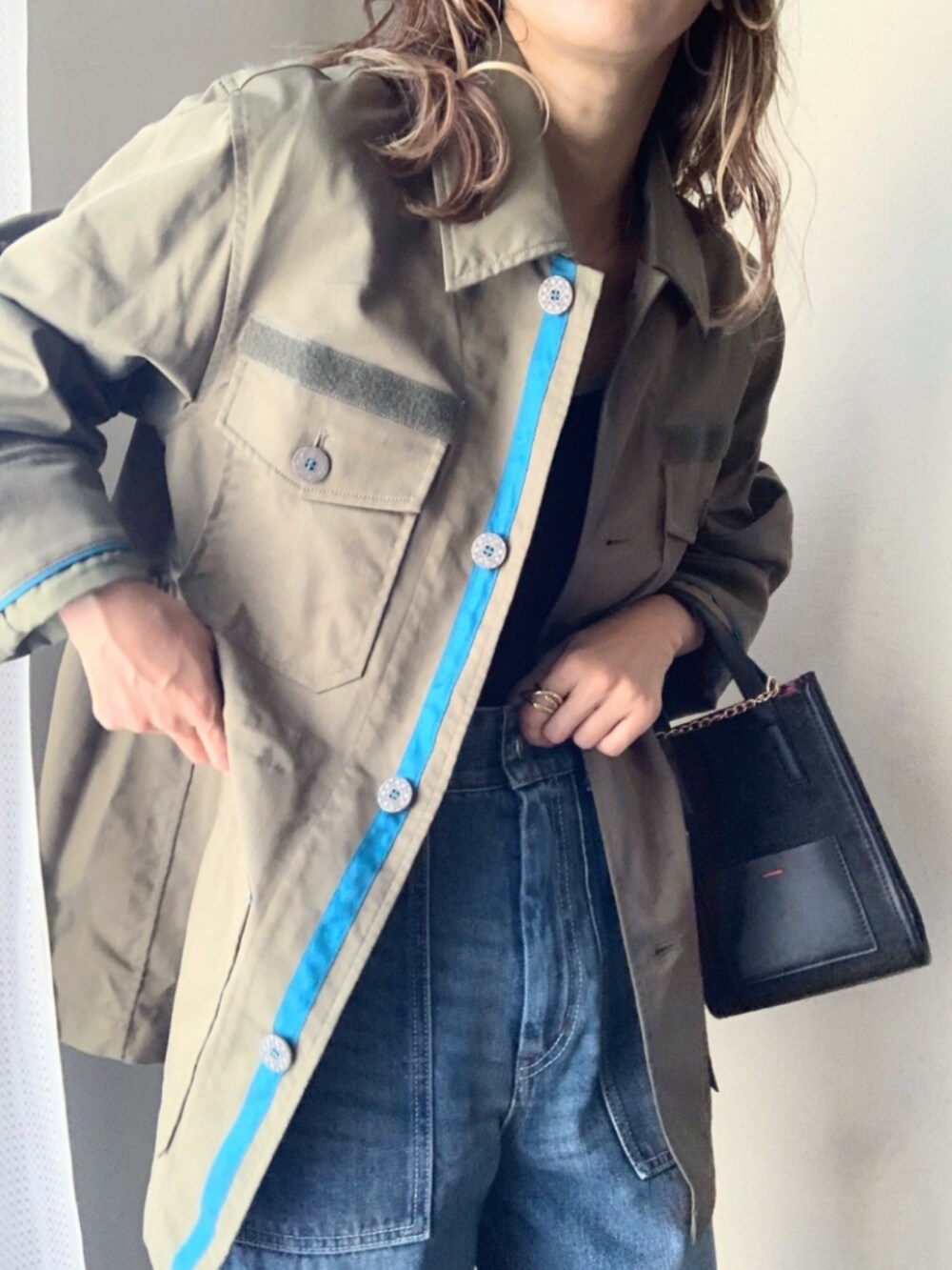 ブルー系のデニムパンツ、グリーン系のミリタリージャケット、ブラック系のショルダーバッグを着用したレディースの秋コーディネートの4枚目の写真