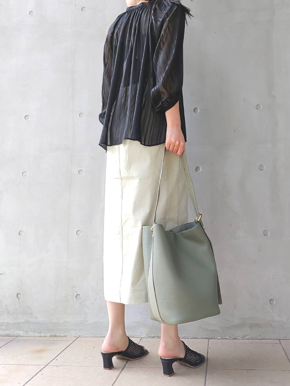 ブラック系のシャツ/ブラウス、グリーン系のスカート、ブラック系のサンダルを着用したレディースの春コーディネートの2枚目の写真