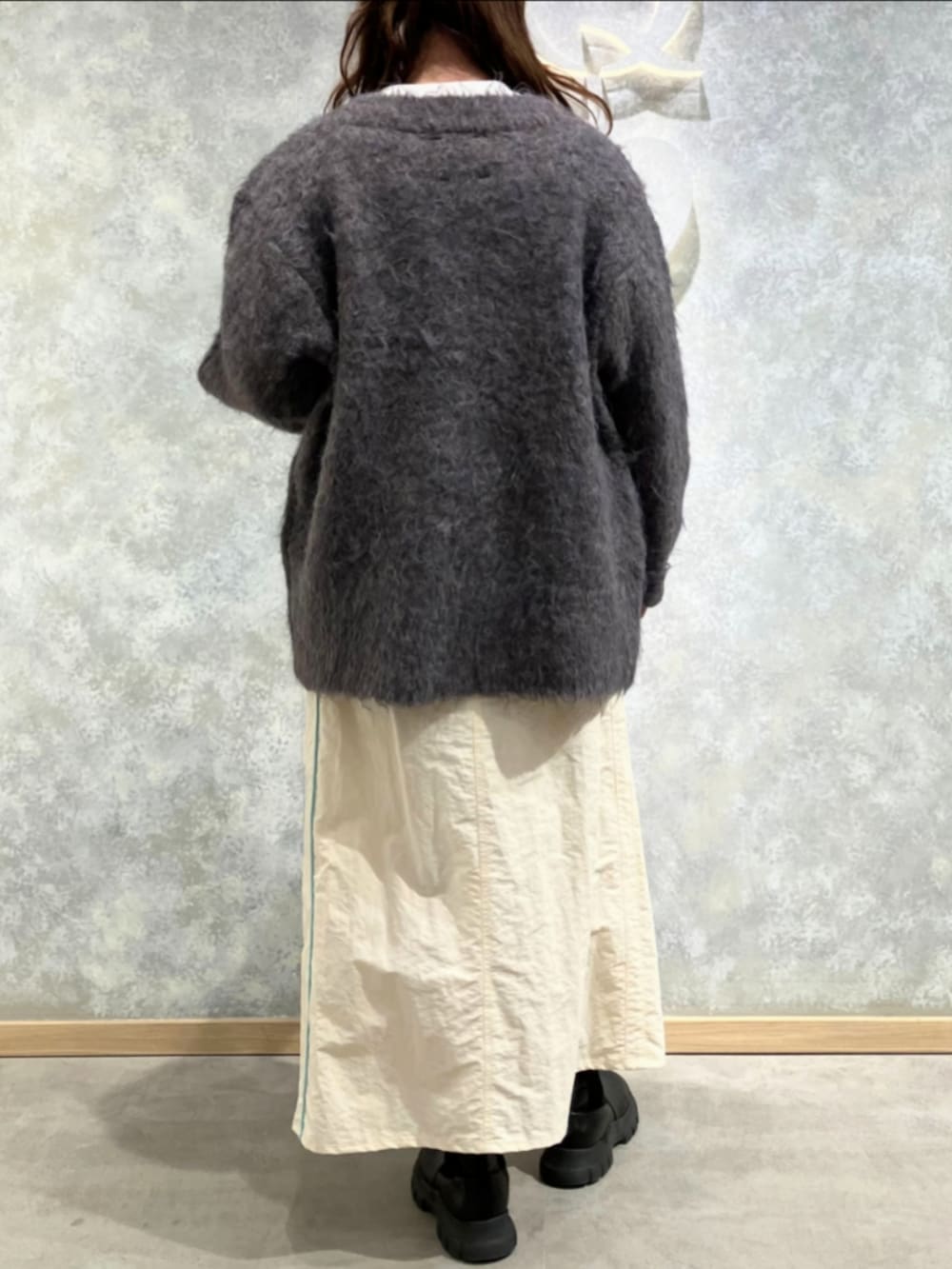 ブラウン系のカーディガン/ボレロ、ホワイト系のニット/セーター、ホワイト系のデニムスカートを着用したレディースの冬コーディネートの3枚目の写真