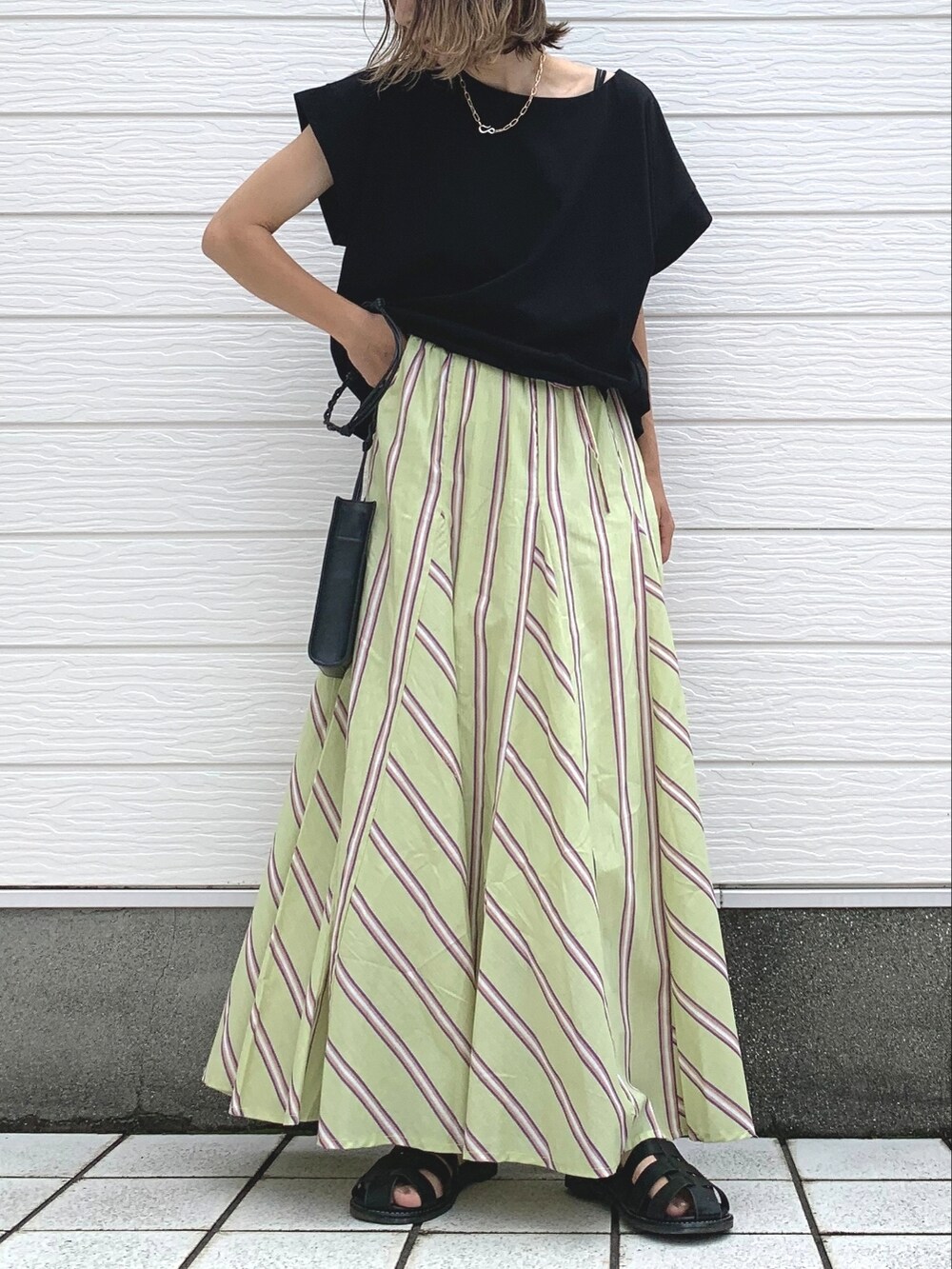 ブラック系のTシャツ/カットソー、ブラック系のサンダル、グリーン系のスカートを着用したレディースの夏コーディネートの2枚目の写真