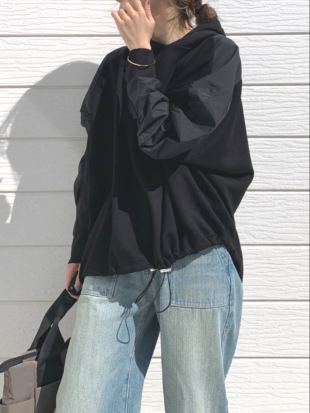 ブルー系のデニムパンツ、グリーン系のトートバッグ、ホワイト系のスニーカーを着用したレディースの春コーディネートの3枚目の写真