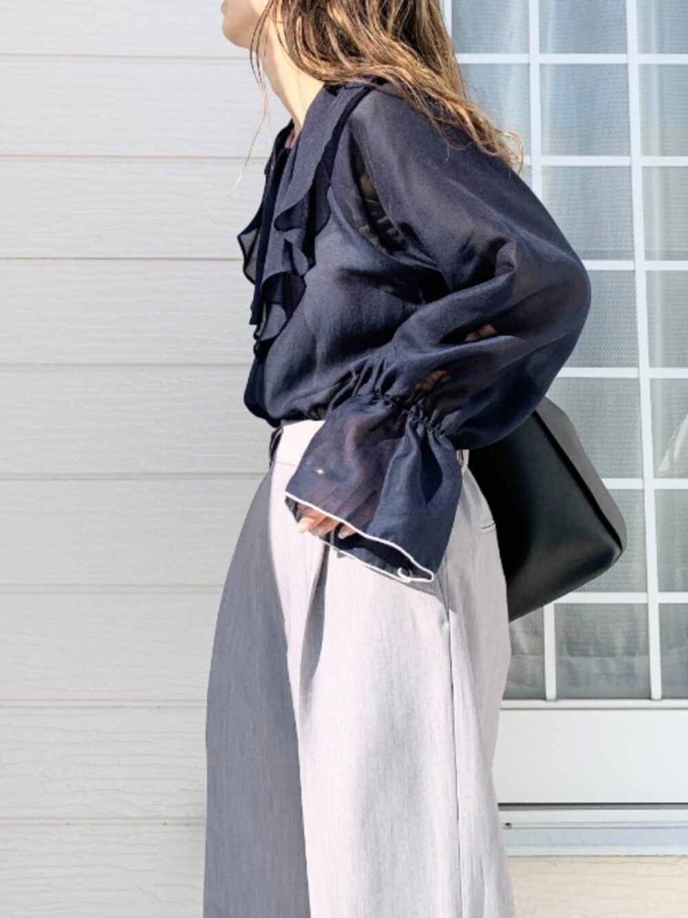 グレー系のスラックス、ブラック系のトートバッグ、ブルー系のシャツ/ブラウスを着用したレディースの春コーディネートの4枚目の写真