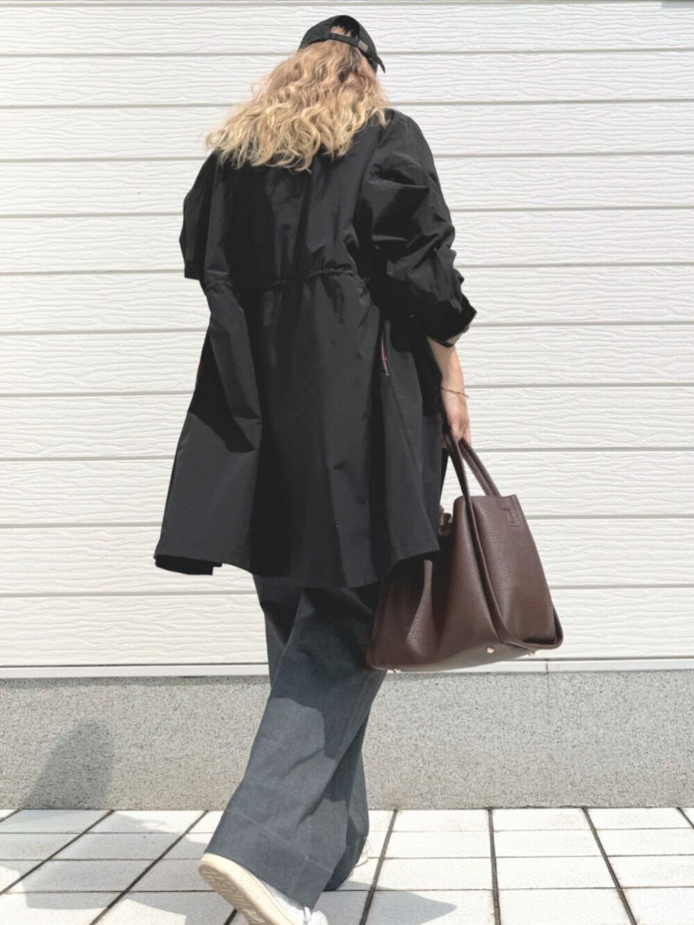 グレー系のデニムパンツ、ブラウン系のハンドバッグ、グレー系のTシャツ/カットソーを着用したレディースの夏コーディネートの2枚目の写真