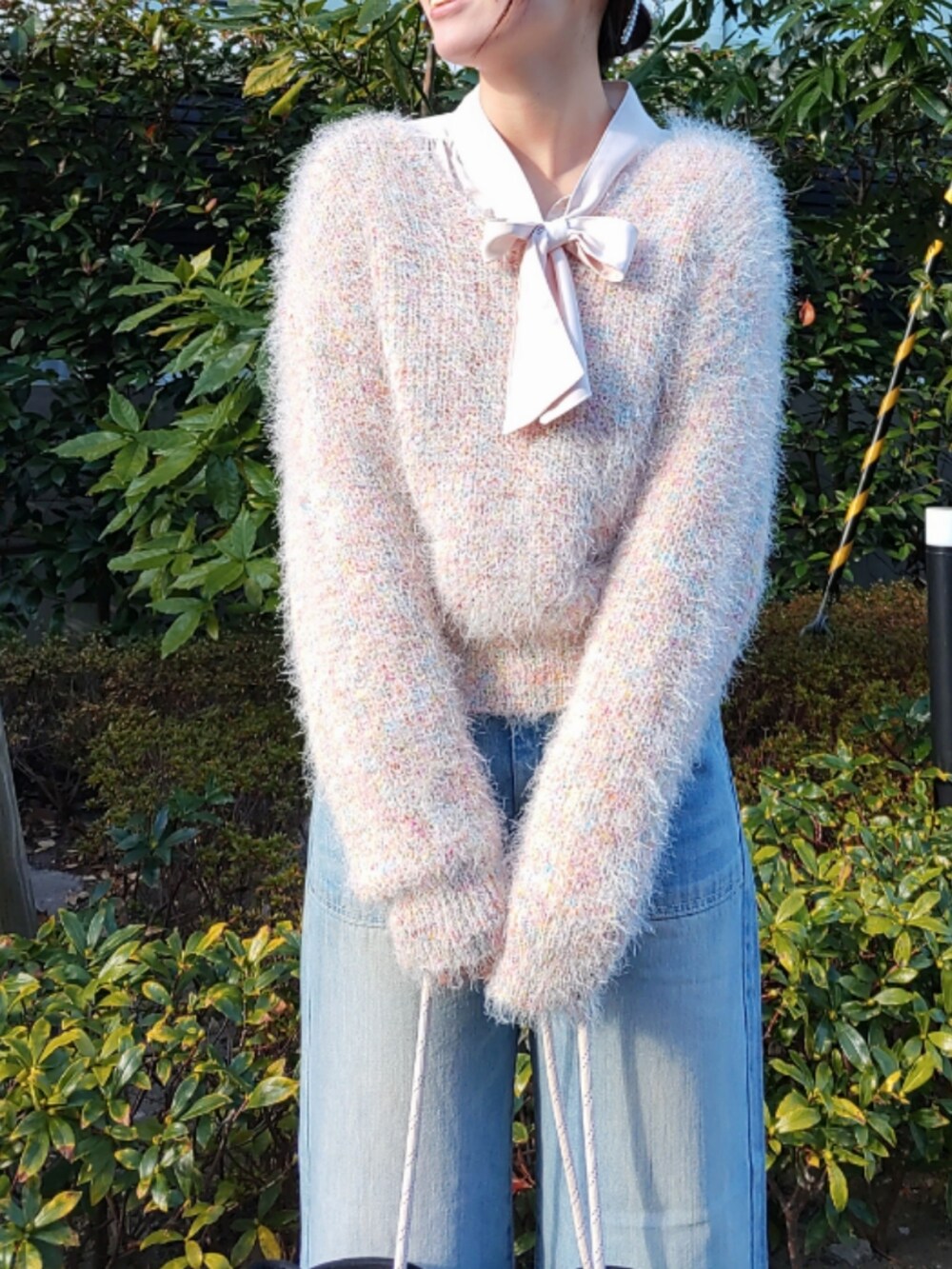ブルー系のデニムパンツ、ブルー系のトートバッグ、ベージュ系のニット/セーターを着用したレディースの冬コーディネートの3枚目の写真