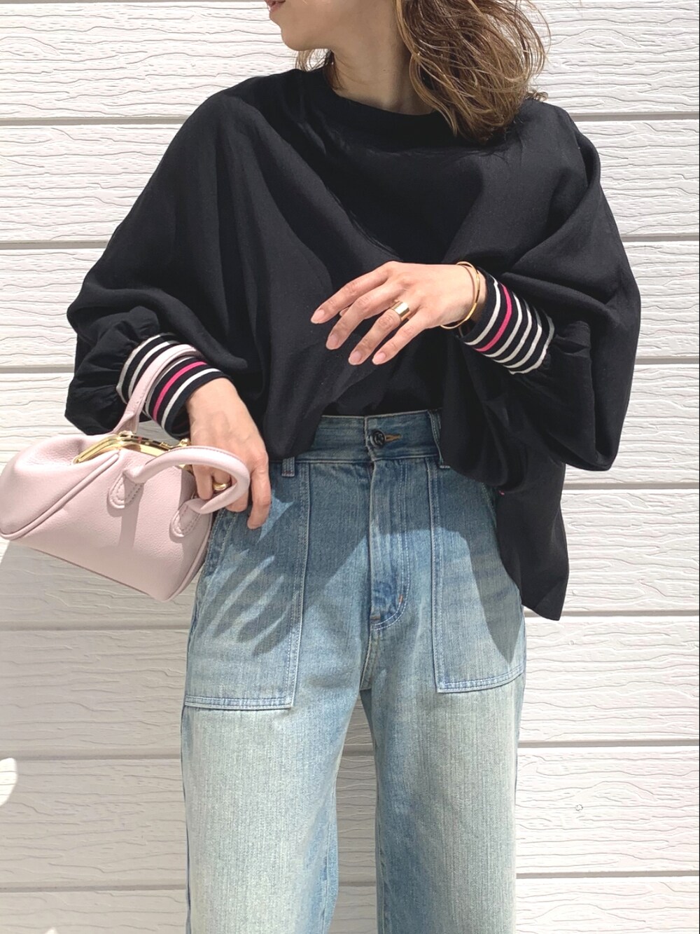 ブルー系のデニムパンツ、ピンク系のショルダーバッグ、ブラック系のシャツ/ブラウスを着用したレディースの春コーディネートの3枚目の写真