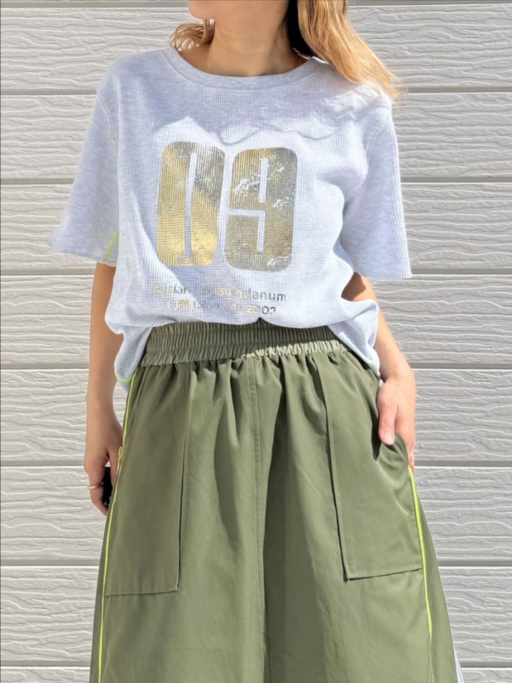 グリーン系のスカート、グレー系のTシャツ/カットソー、ブラック系のキャップを着用したレディースの春コーディネートの5枚目の写真